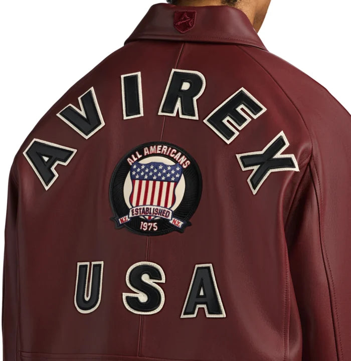 Close-up rear view of Avirex maroon bomber showing AVIREX lettering, central heritage crest and USA appliqué