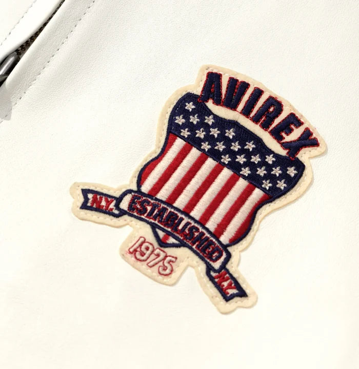 Close-up of white Avirex Icon leather jacket showing embroidered Established 1975 American shield chest patch
