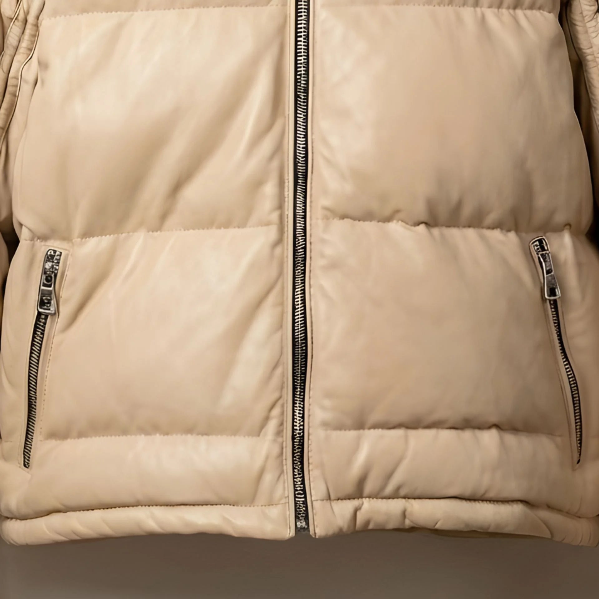 Detail of front zip pockets on beige leather puffer jacket.