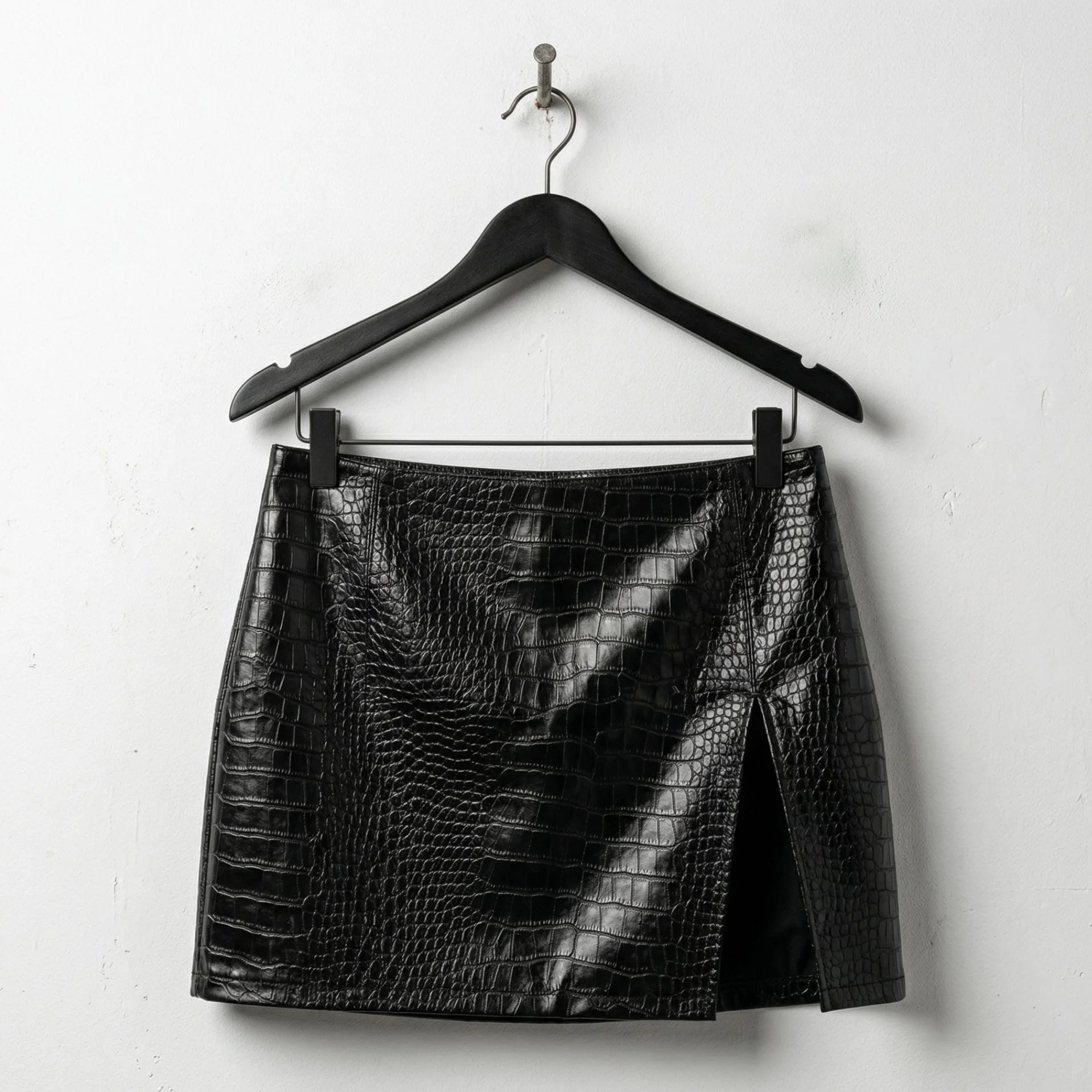Front view of black croc embossed mini leather skirt with side slit