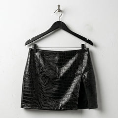 Front view of black croc embossed mini leather skirt with side slit