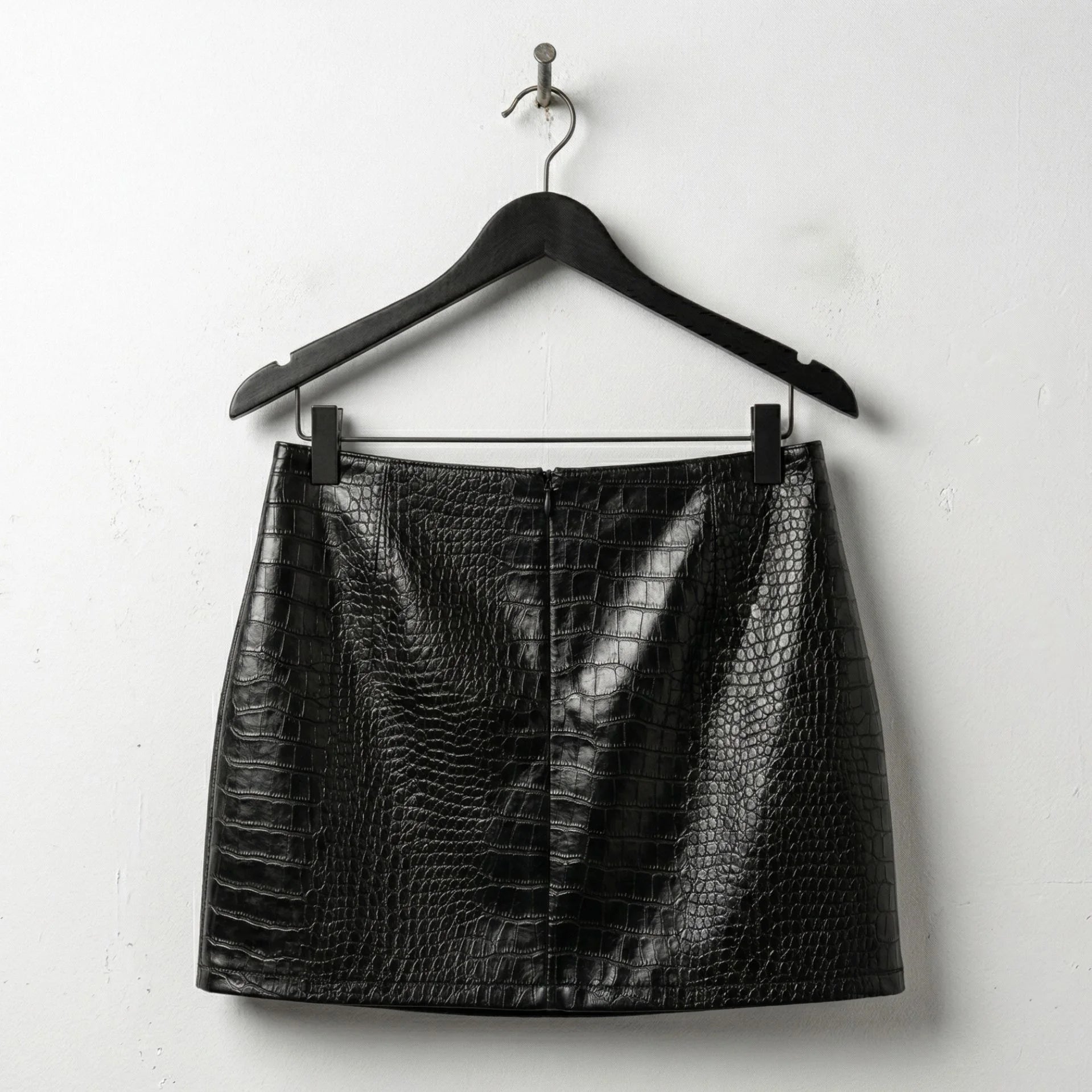 Back view of black crocodile embossed mini leather skirt on hanger