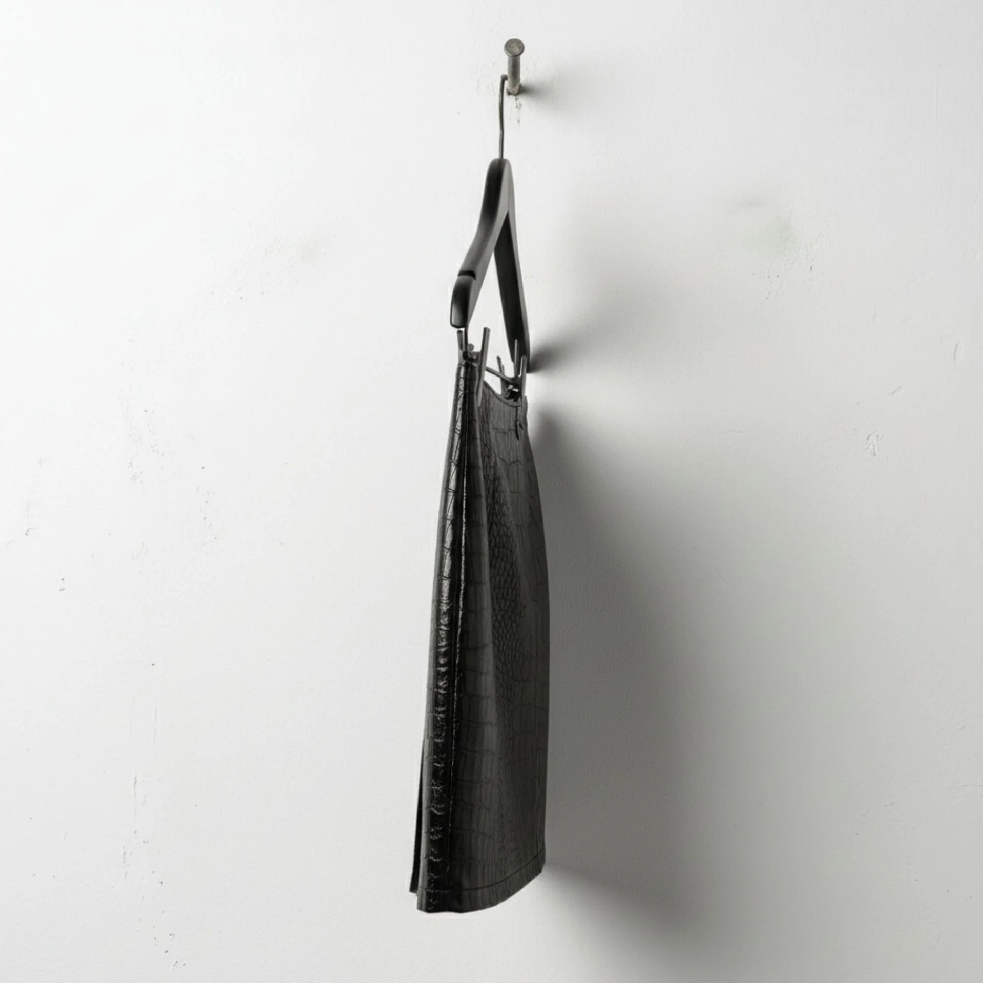 Side profile of black croc leather mini skirt showing slim silhouette