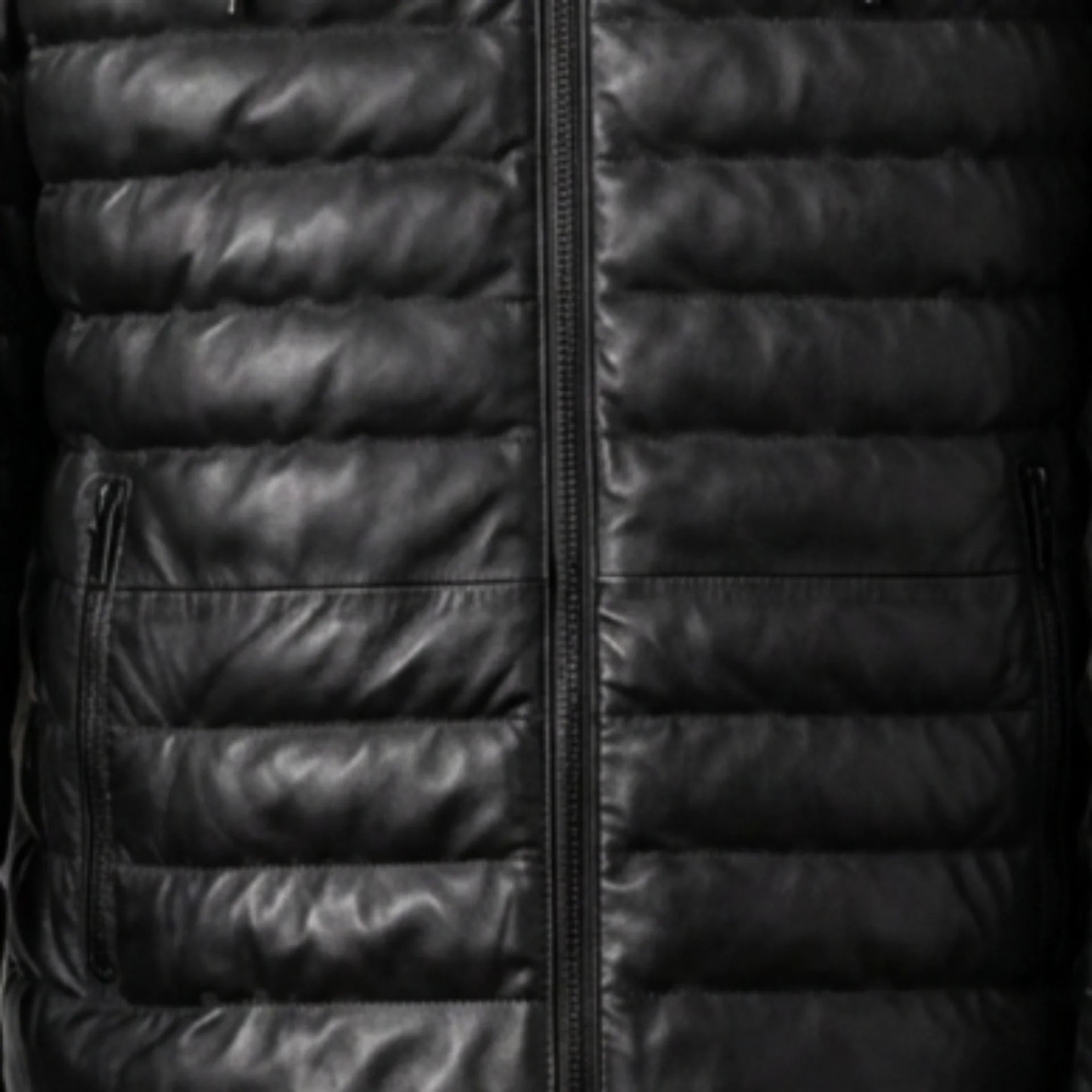 Close-up of vertical zip pockets and quilted texture on black leather puffer jacket
