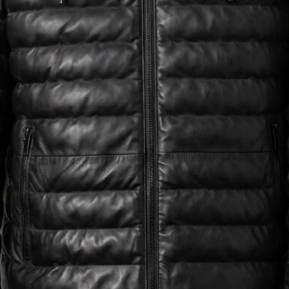 Close-up of vertical zip pockets and quilted texture on black leather puffer jacket