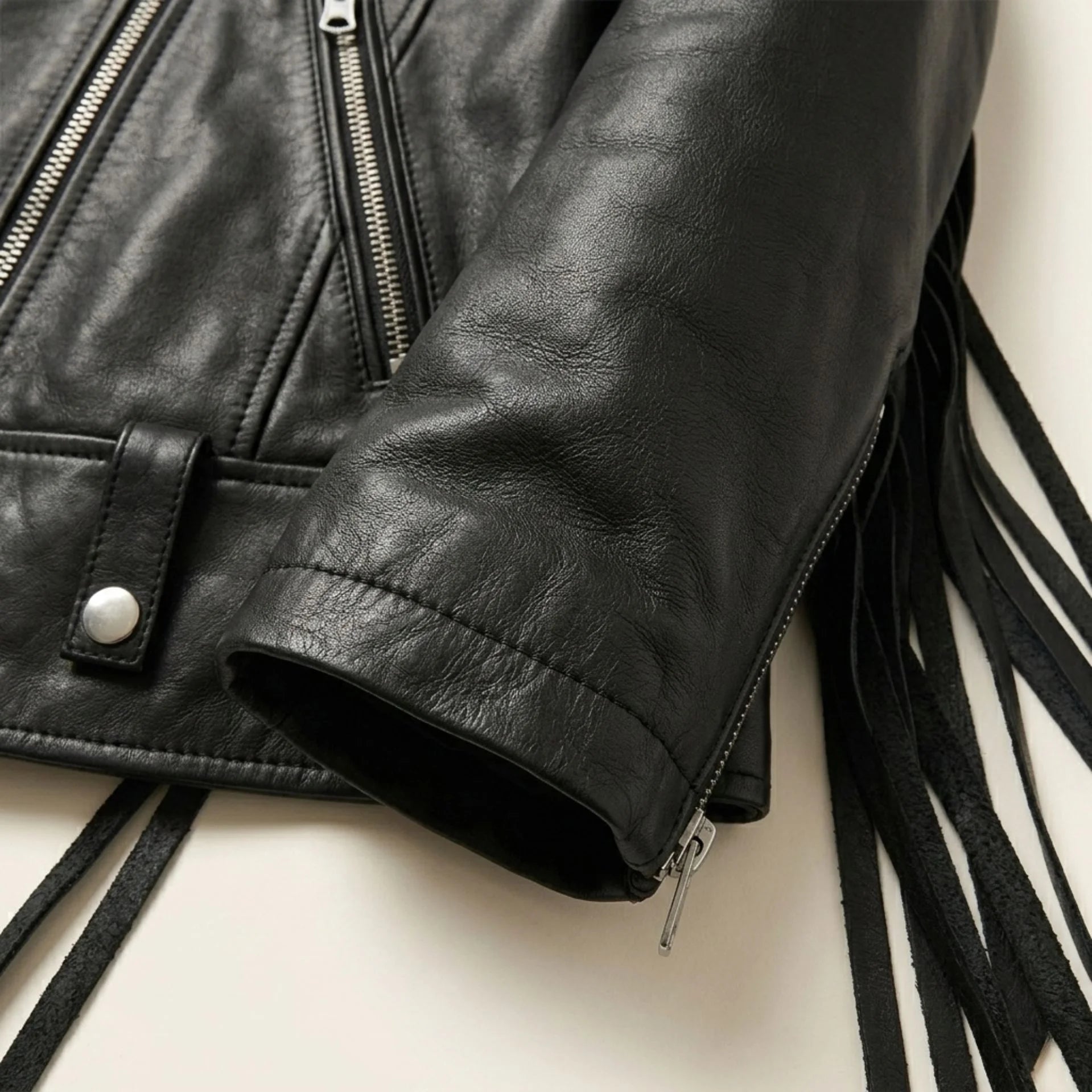 Close up of sleeve zipper and leather fringe on black womens biker jacket