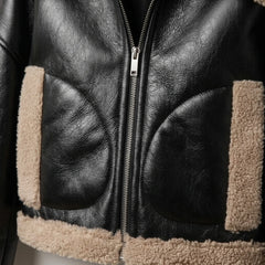 Close-up of zipper and beige shearling pockets on black leather cropped jacket