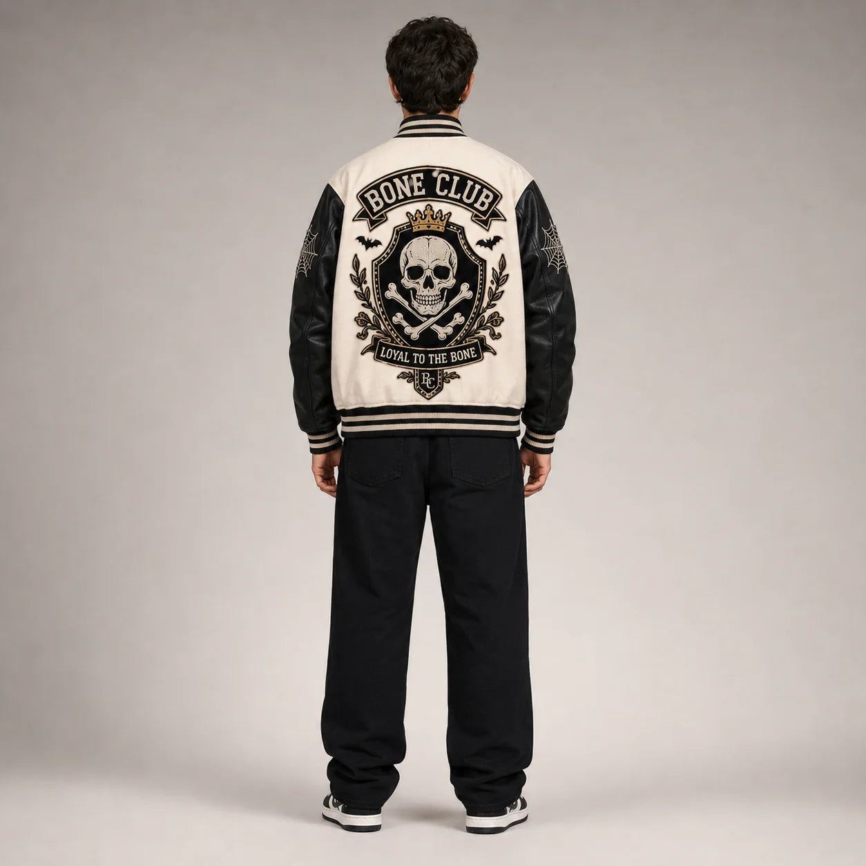 Back studio view of Bone Club varsity jacket with large crowned skull, crossbones, bats and Loyal to the Bone embroidery