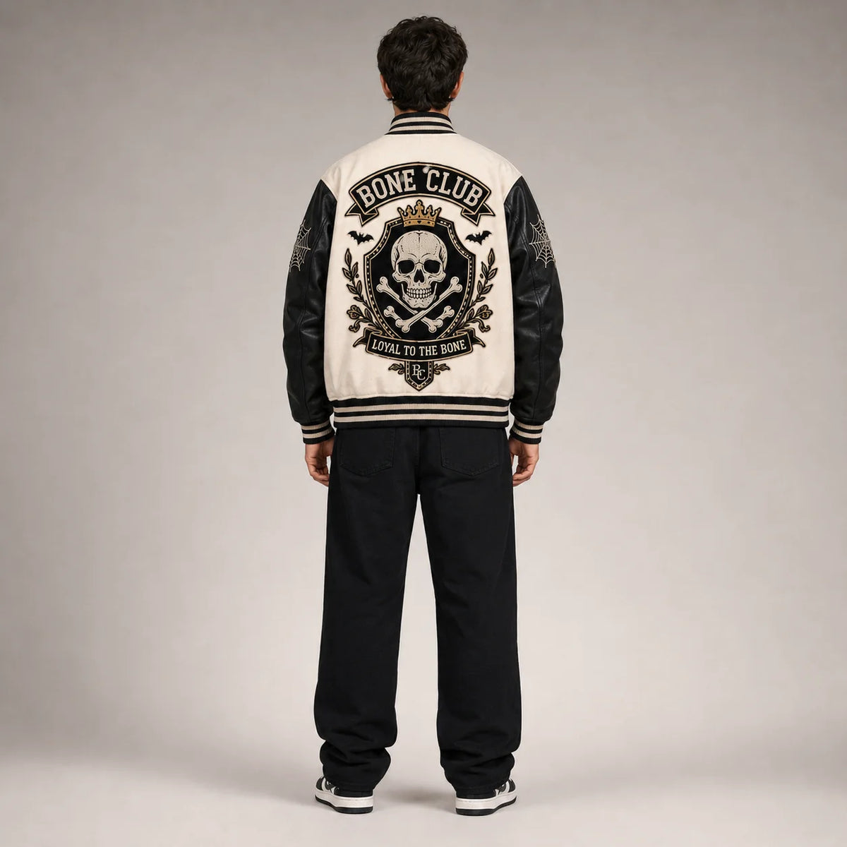Back studio view of Bone Club varsity jacket with large crowned skull, crossbones, bats and Loyal to the Bone embroidery