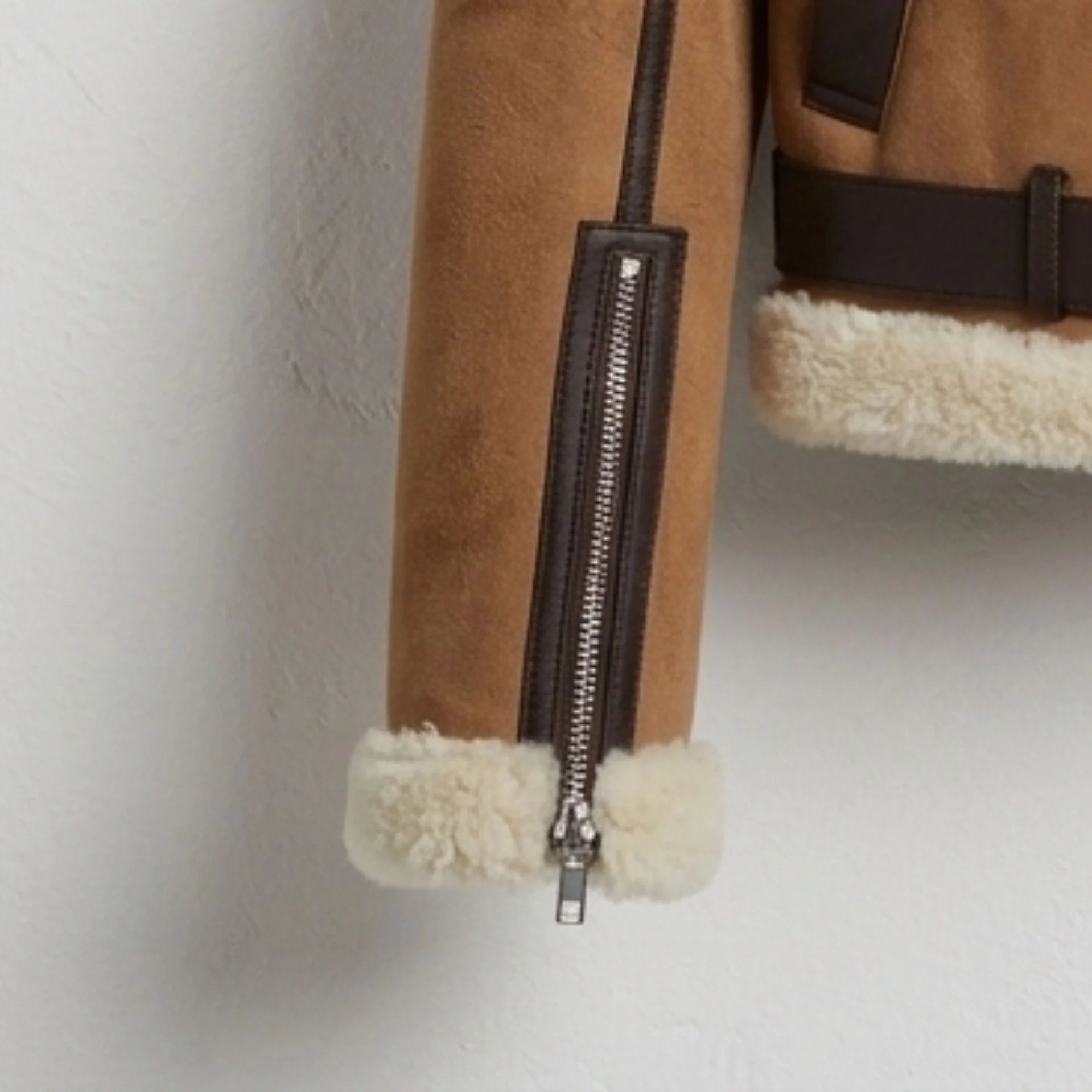 Front zipper, welt pockets and belted hem on brown sherpa leather jacket