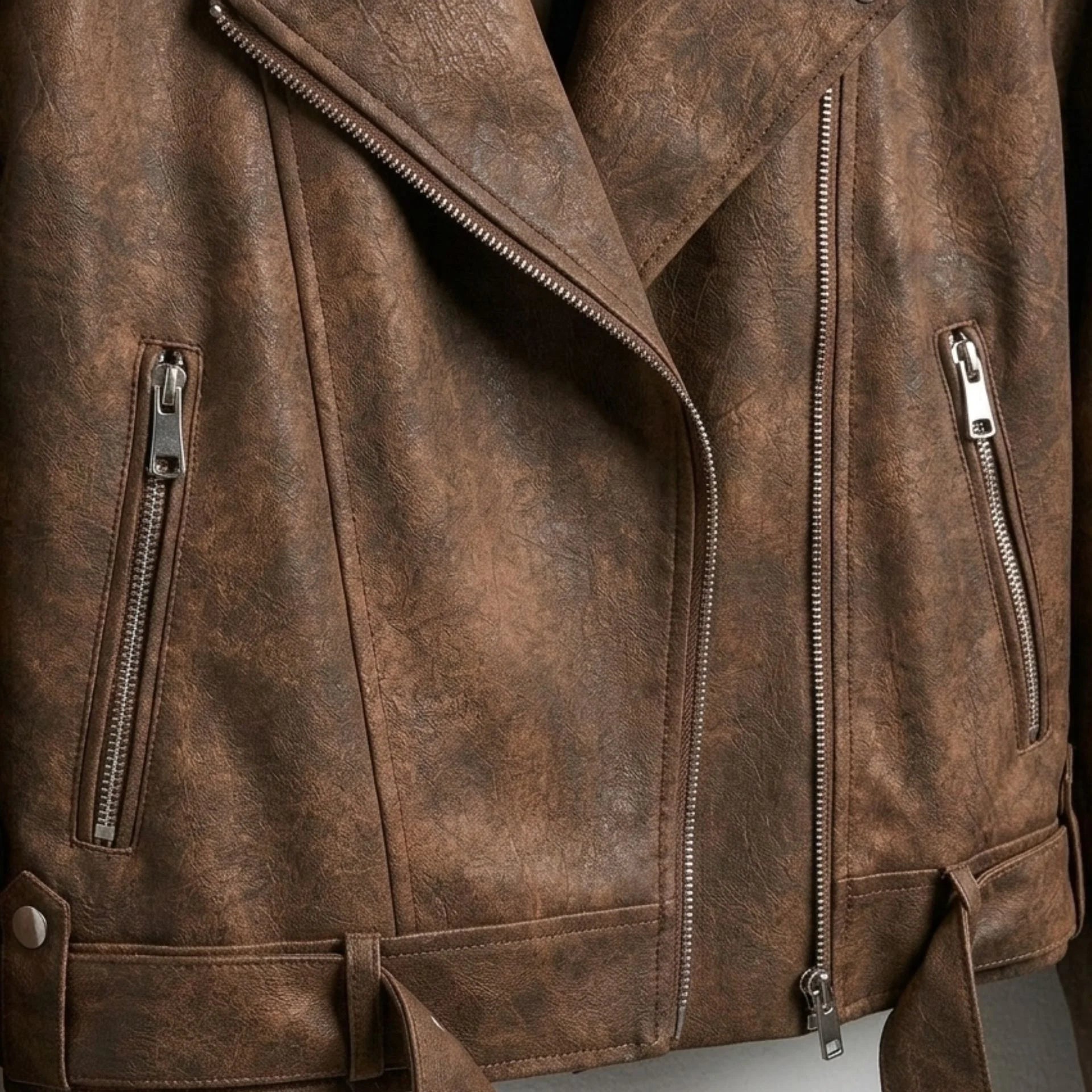 Front zipper and pocket hardware detail on womens brown biker leather jacket