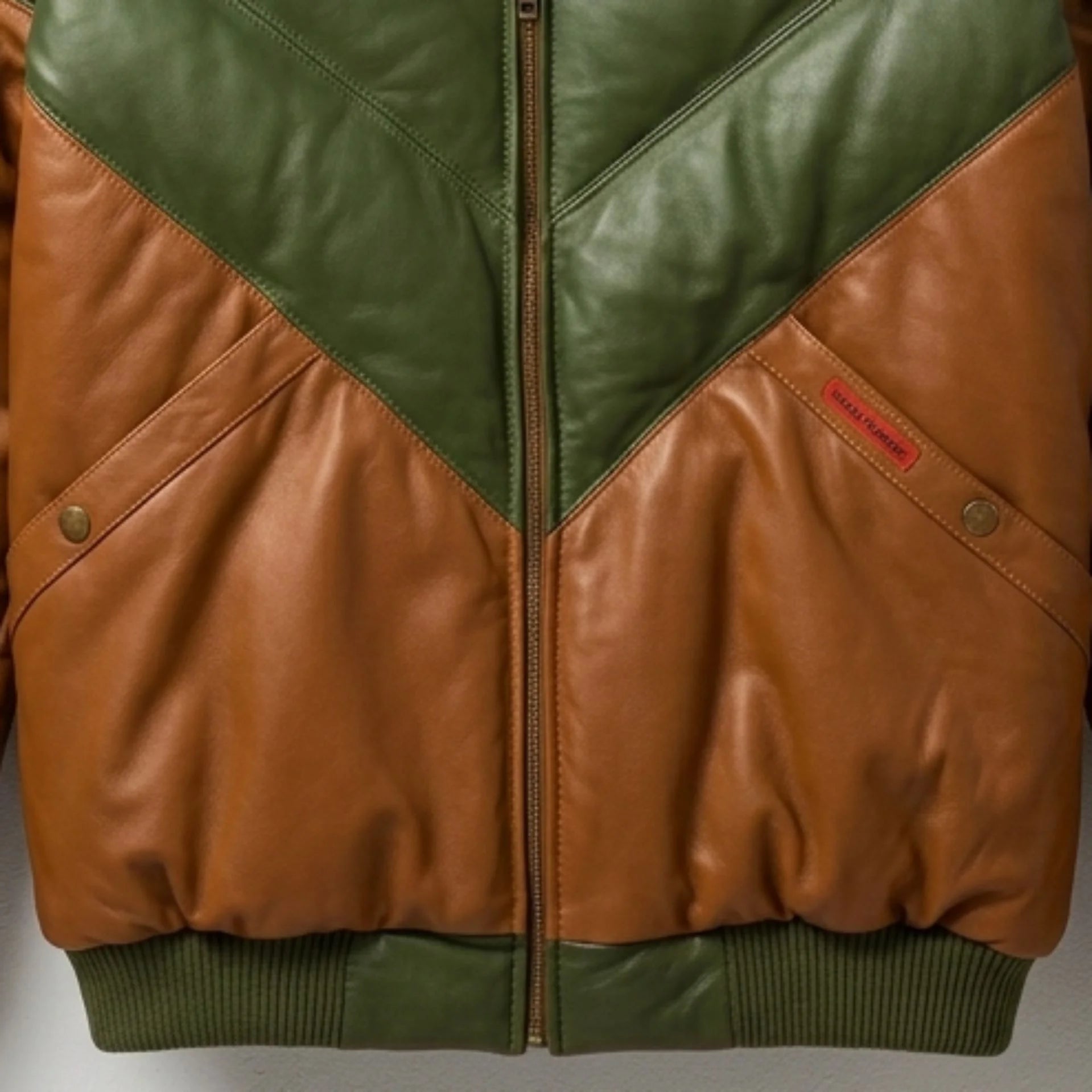 Close-up of snap-button pocket and V-panel design on leather puffer jacket