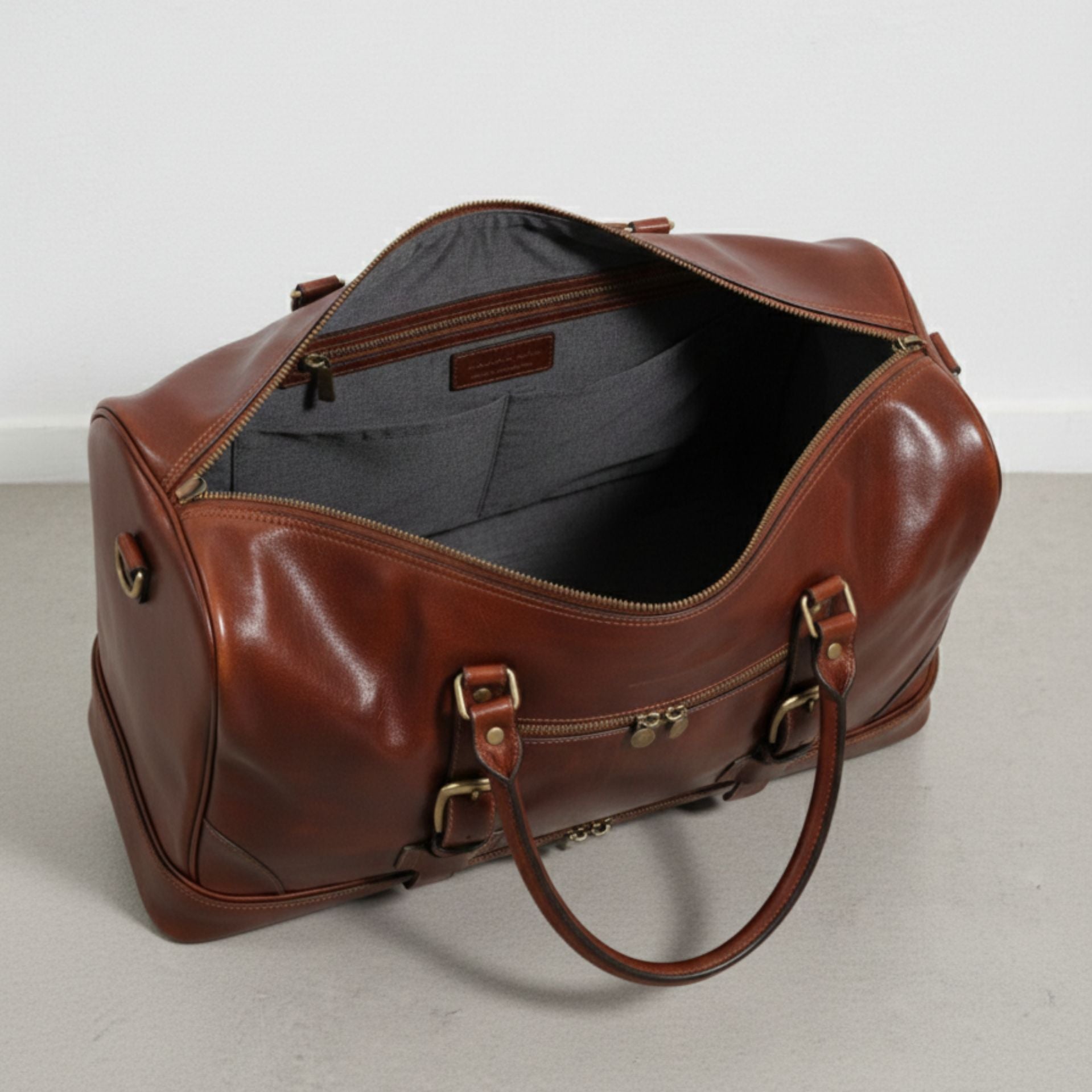 interior view of brown leather duffle bag with grey lining and inside zip pocket.