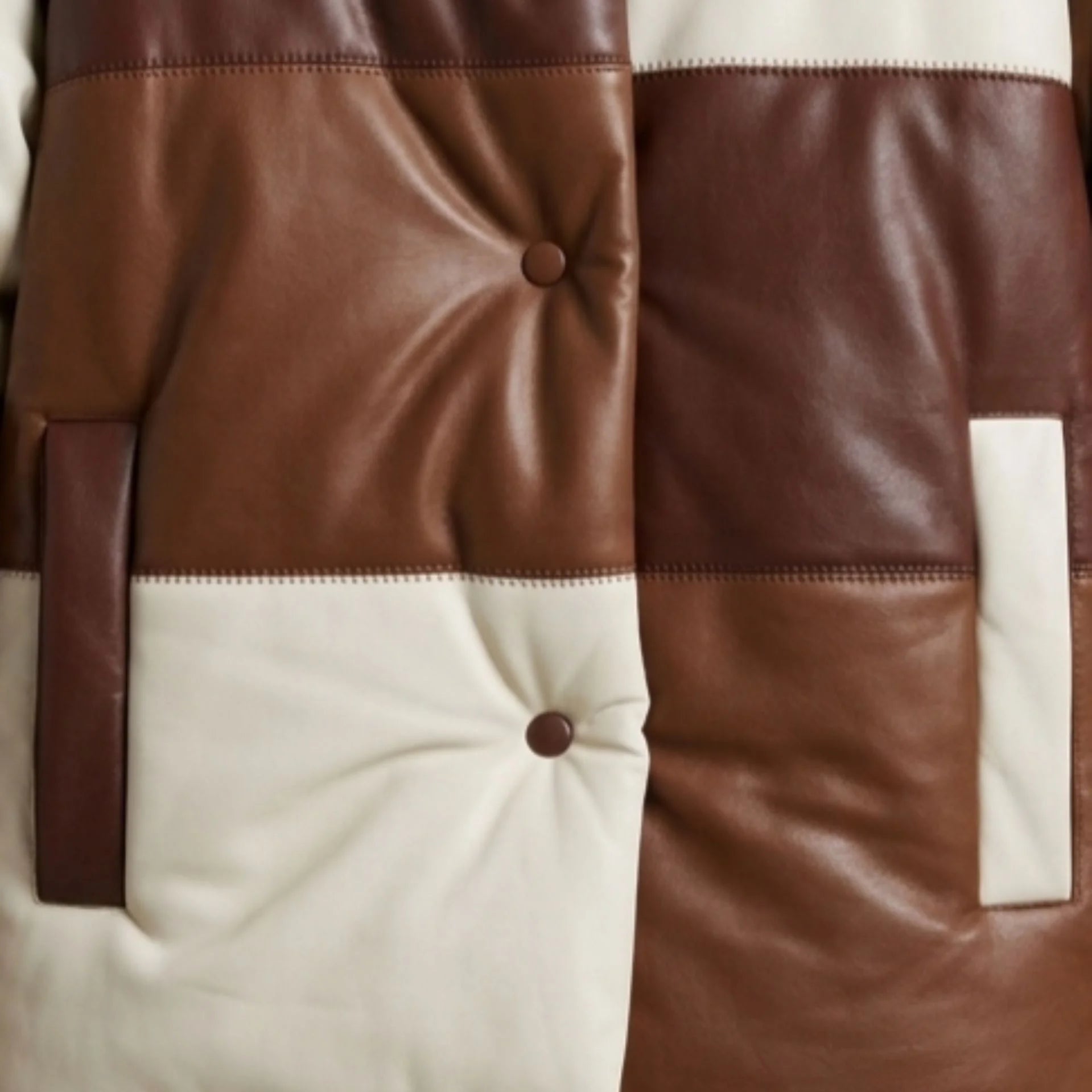 Close-up of patch pocket and tufted texture on brown leather puffer jacket
