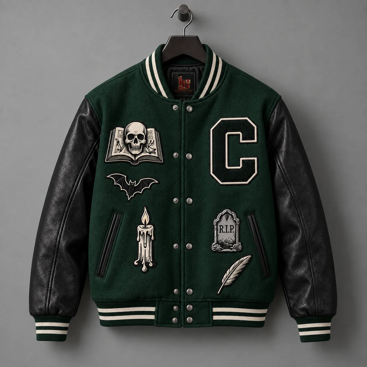 Front hanger view of forest green varsity jacket with genuine black leather sleeves and gothic embroidery