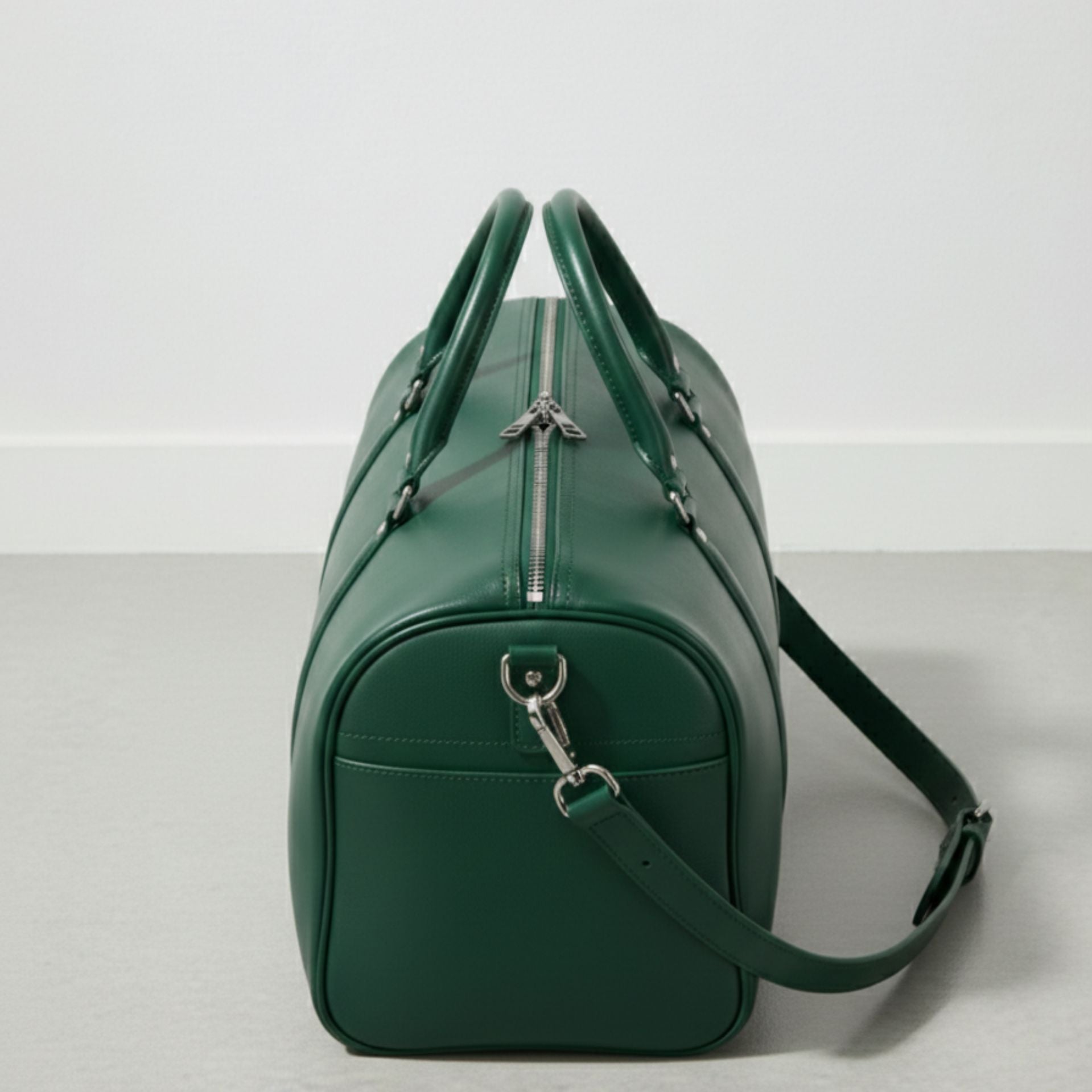 end view green leather travel duffle with top zipper and shoulder strap attached.