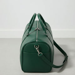end view green leather travel duffle with top zipper and shoulder strap attached.