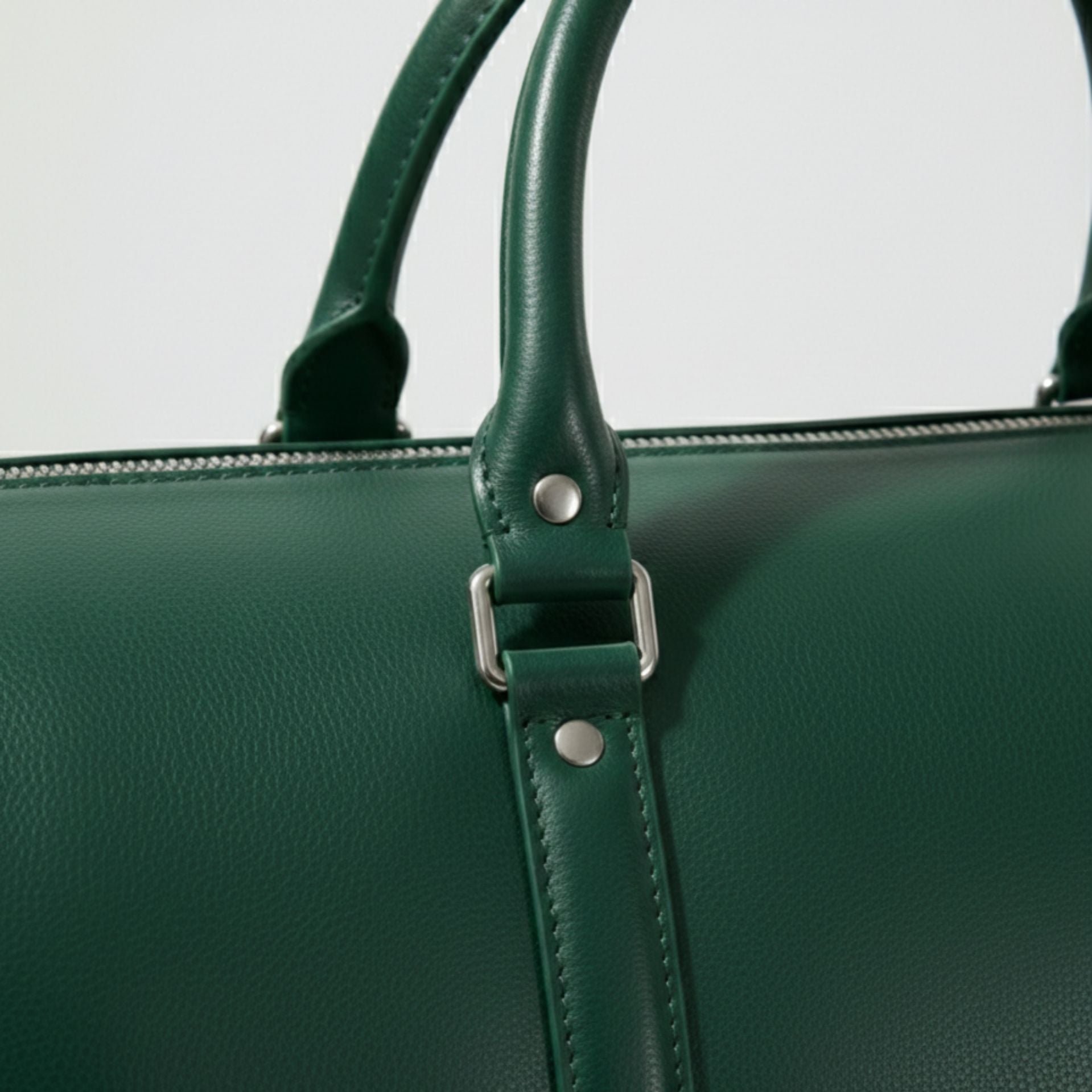close up of rolled leather handles and metal hardware on green duffle bag.