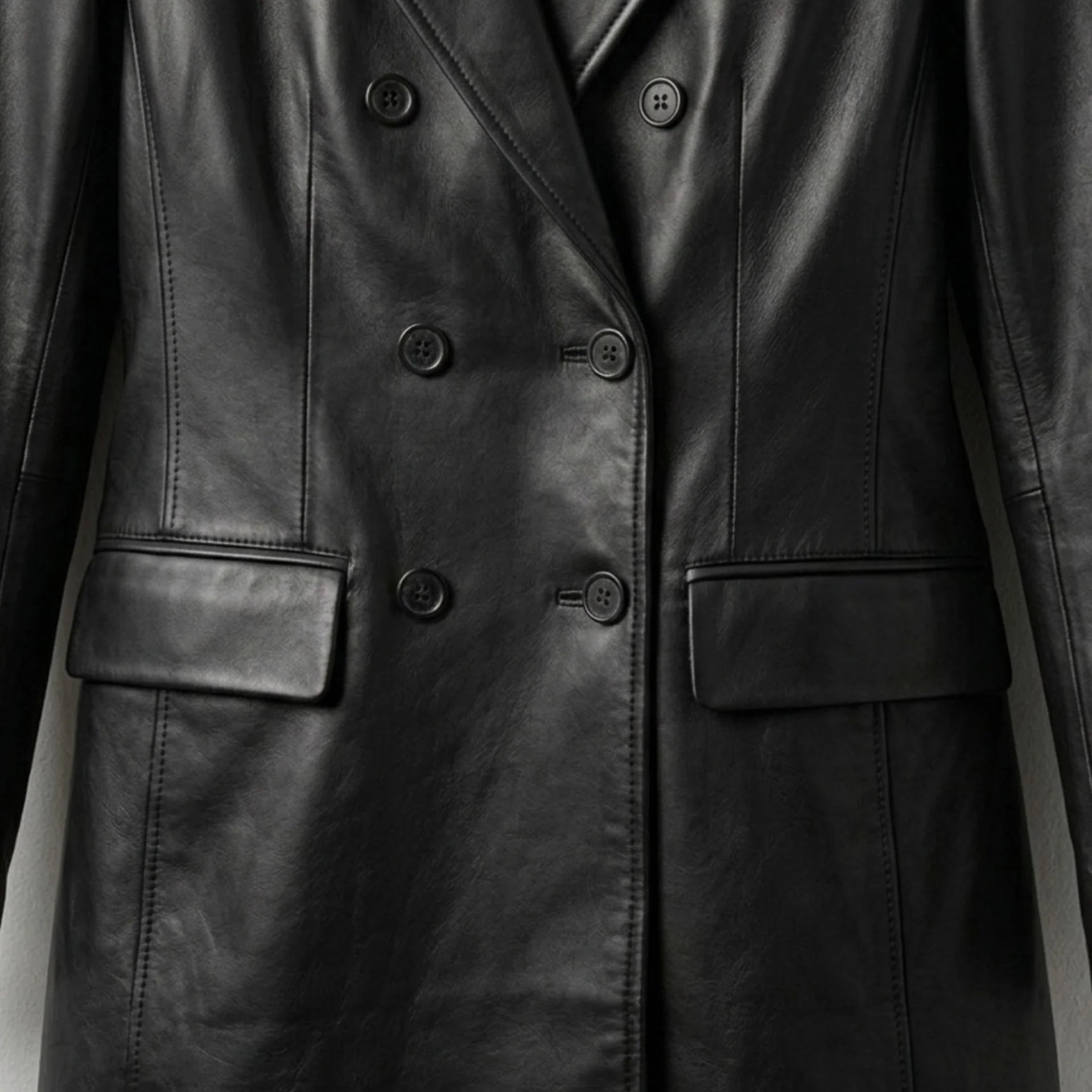Double breasted buttons and flap pockets on women’s black leather coat