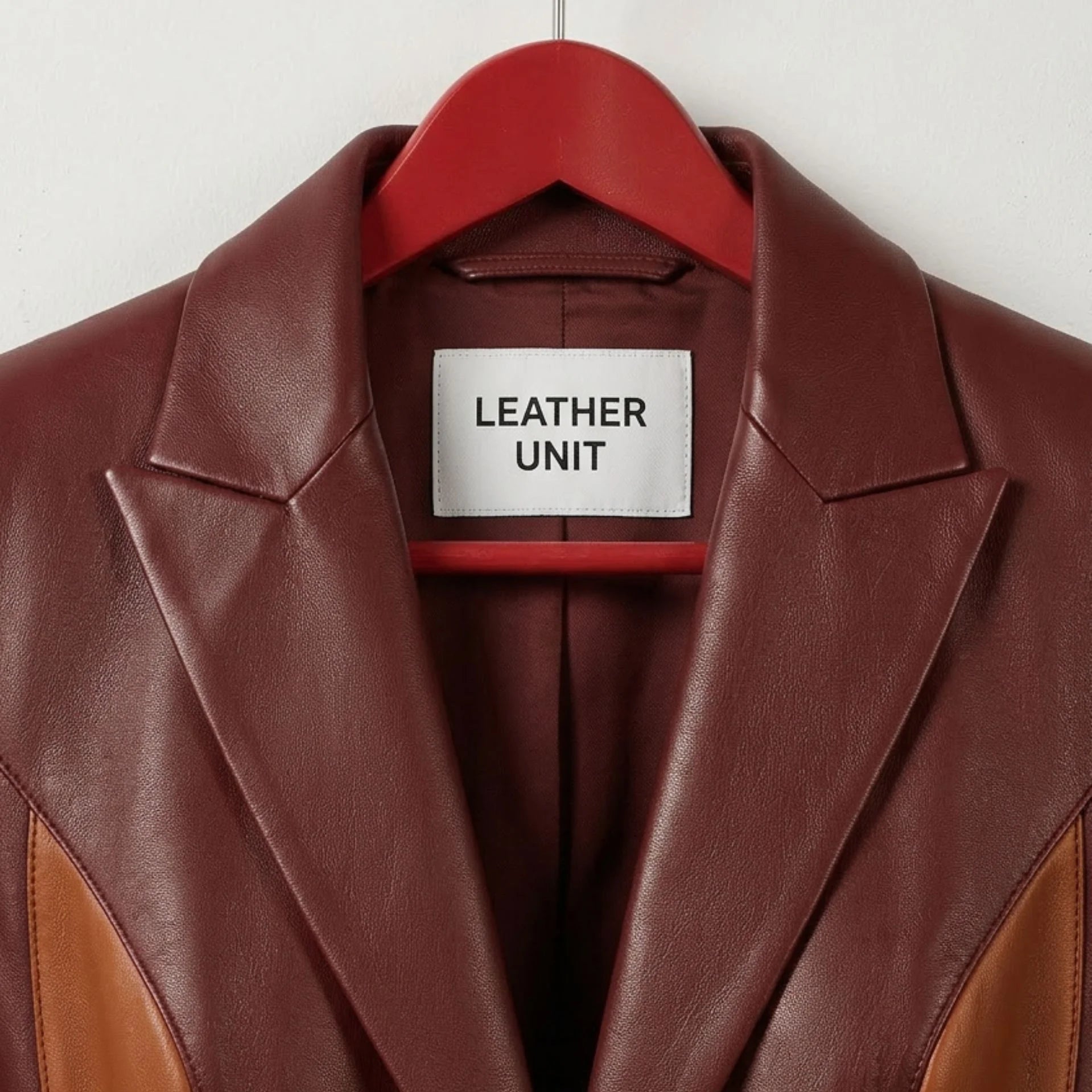 Close up of notched lapels and Leather Unit label on burgundy leather blazer
