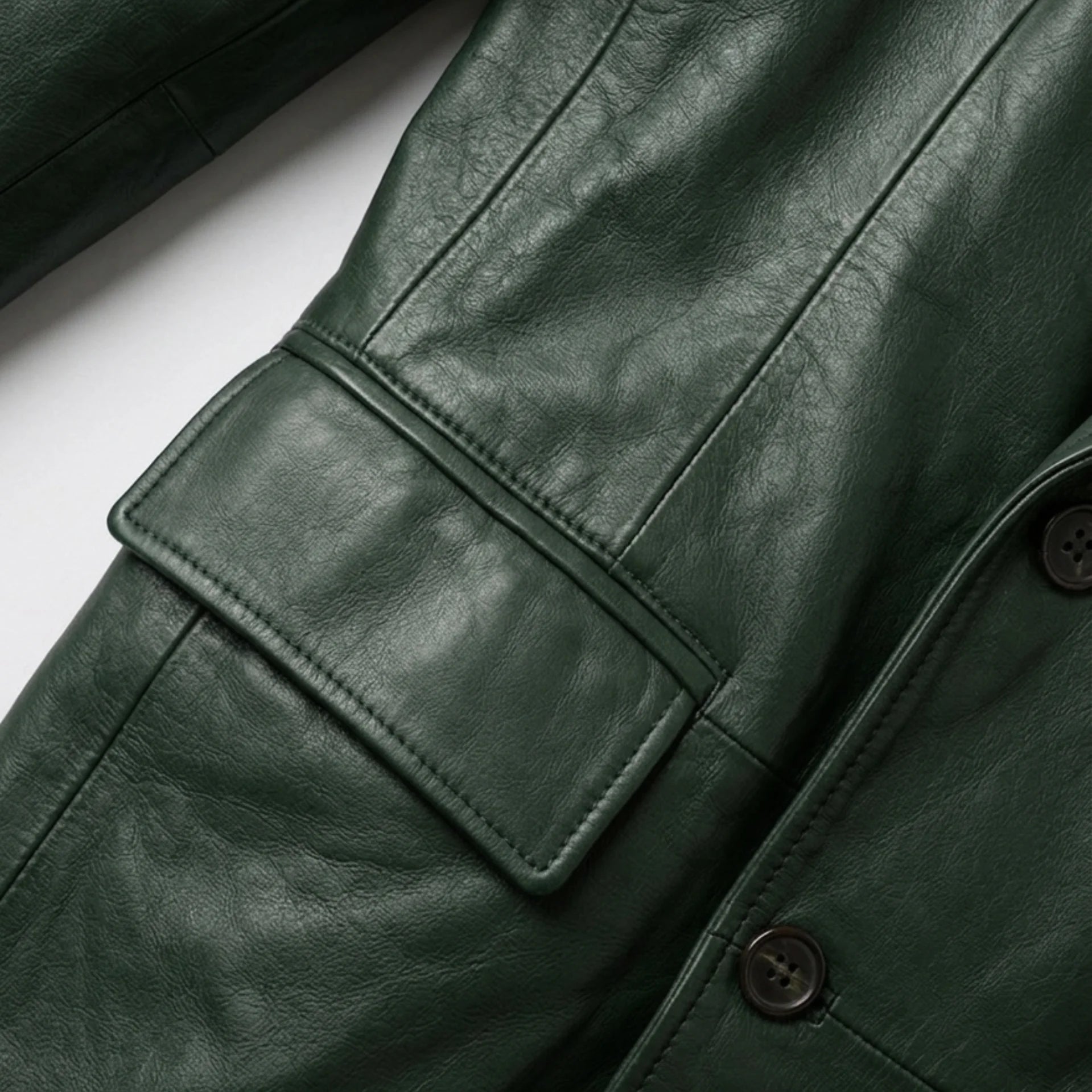 Close view of front flap pocket and buttons on men’s green leather blazer
