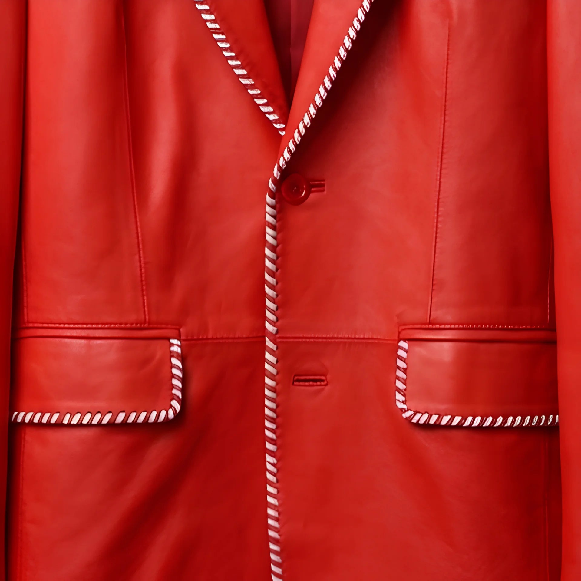 Detail of white striped trim on pockets and front of men’s red leather blazer
