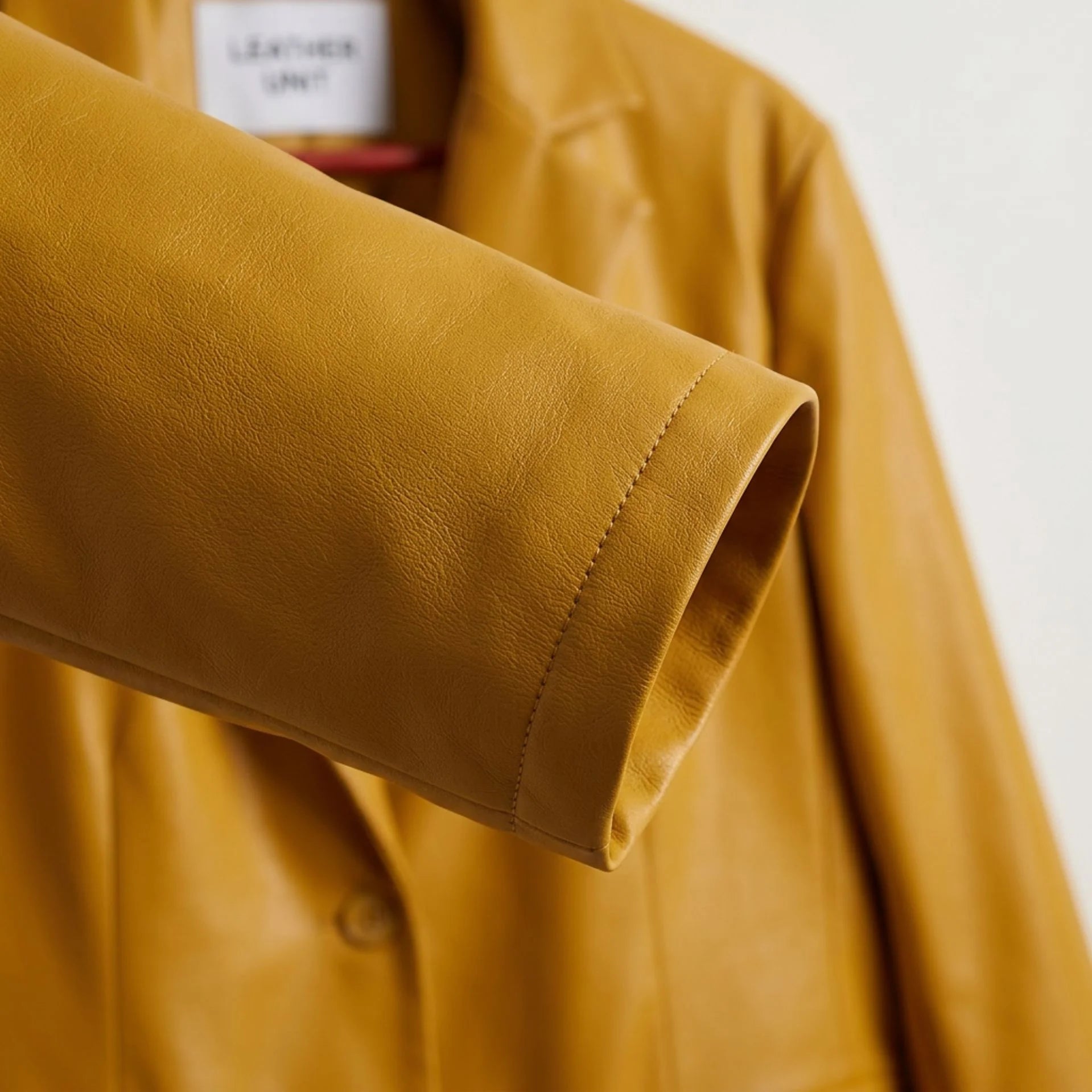 Sleeve cuff detail on smooth mustard yellow vegan leather blazer