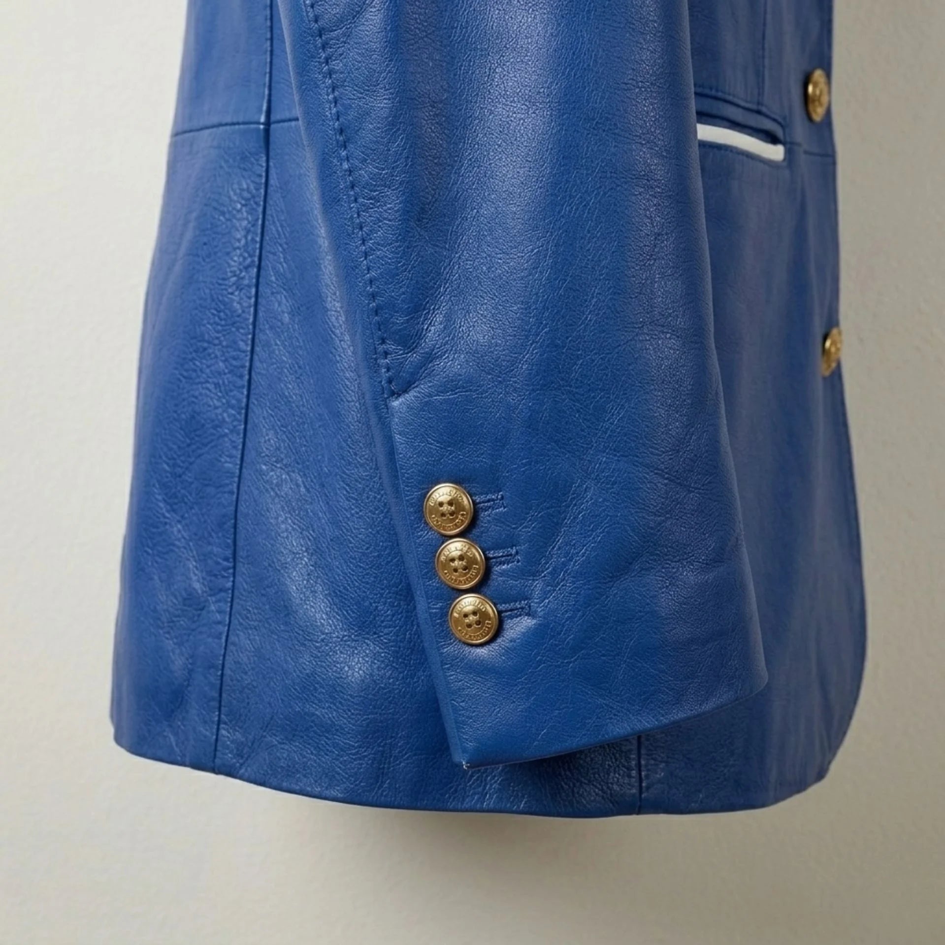 Gold cuff buttons detail on women’s royal blue leather blazer sleeve