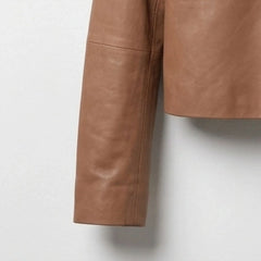 Close-up of sleeve and hem detail on a women's tan cropped leather shirt jacket