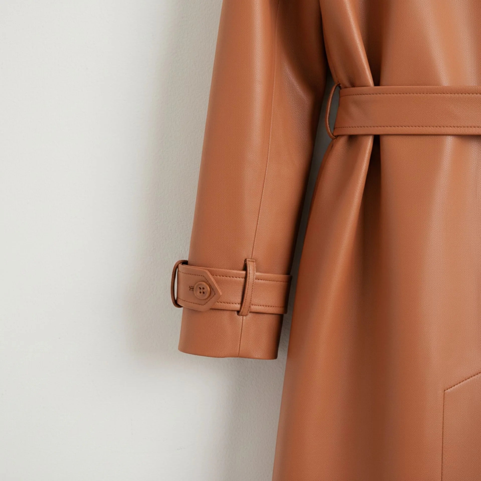 Sleeve cuff strap and buckle detail on women’s tan leather trench coat