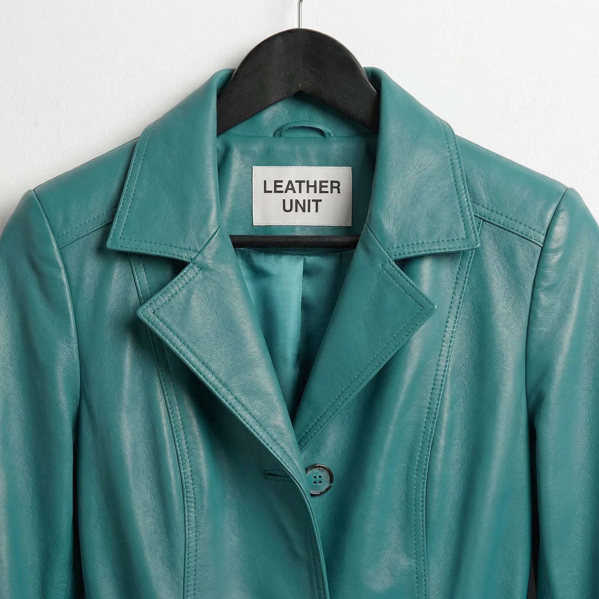 Close up of lapel collar and Leather Unit label on turquoise trench coat
