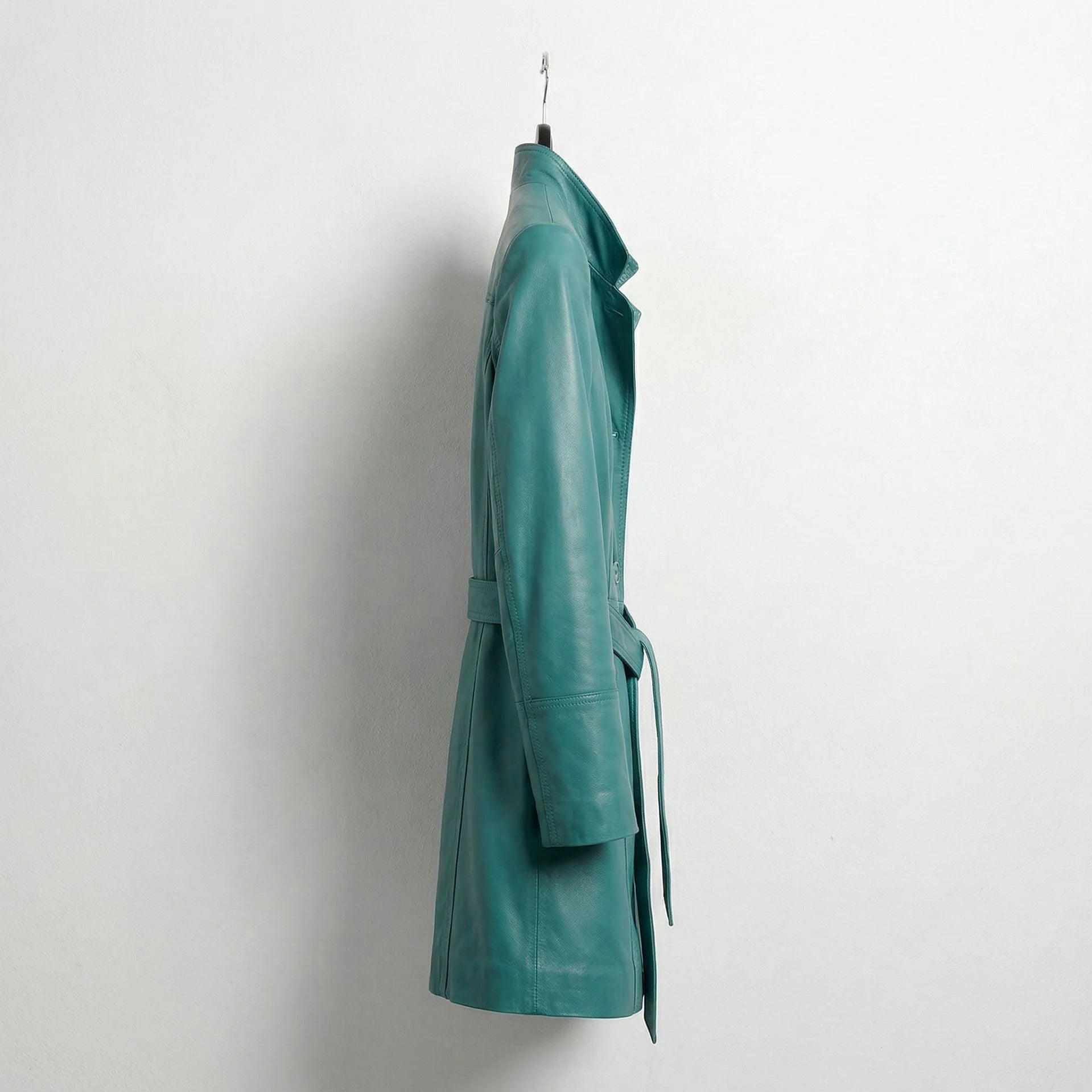 Side profile of mid‑length turquoise leather trench coat with belt