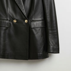 Gold button and flap pocket detail on women’s black leather blazer