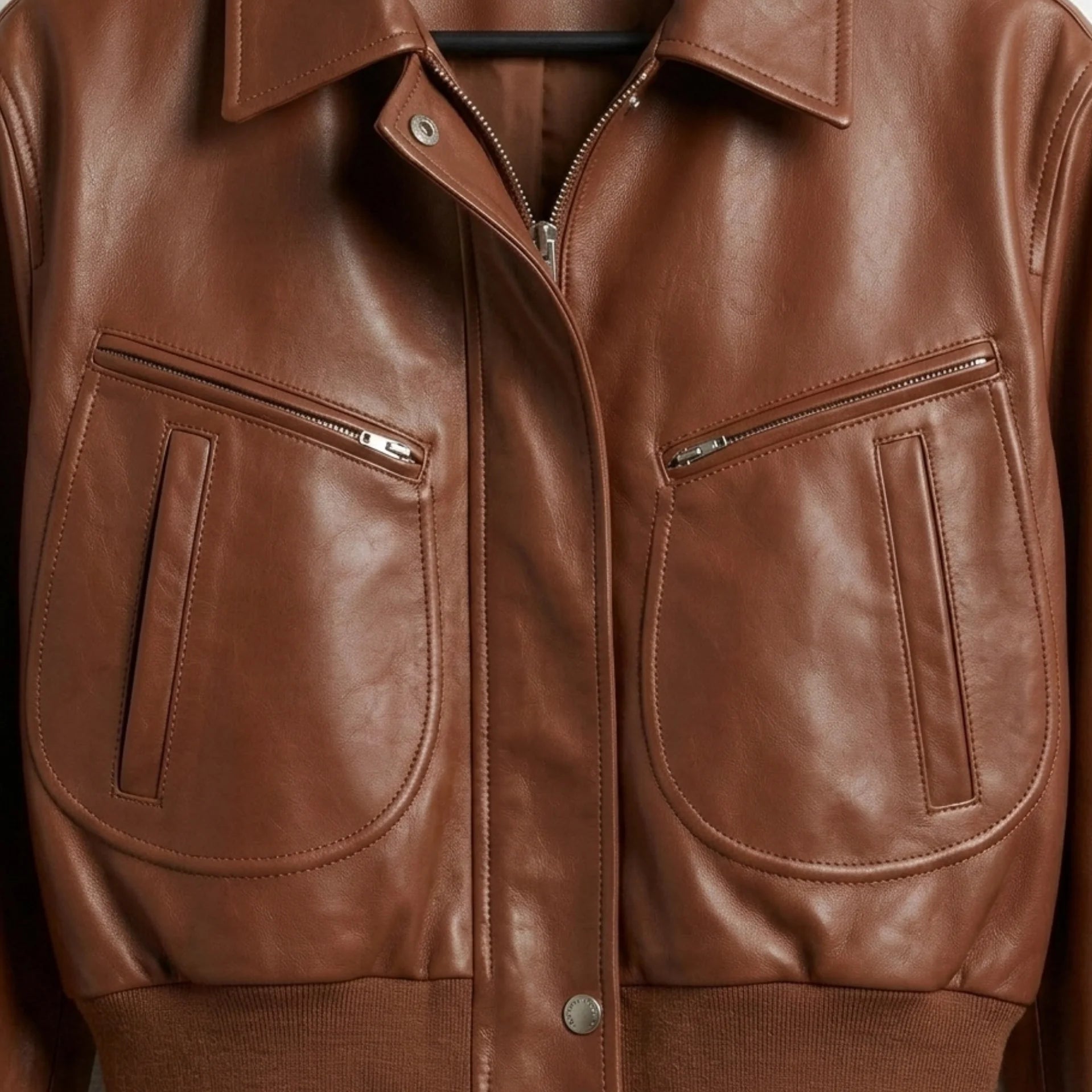 Pocket and zipper detail on women’s brown cropped leather bomber jacket