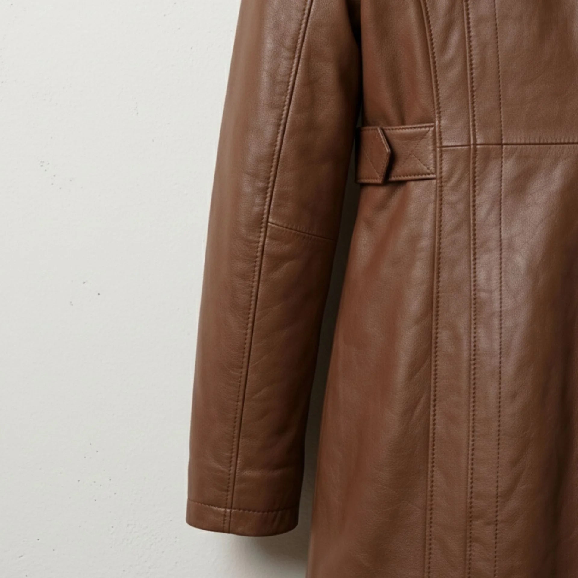 Sleeve and waist tab detail on women’s brown leather hooded coat