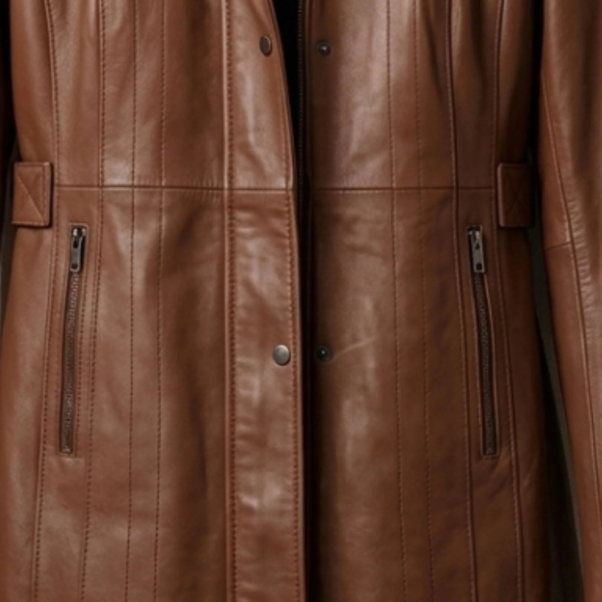 Zip pockets and front closure detail on women’s long brown leather coat