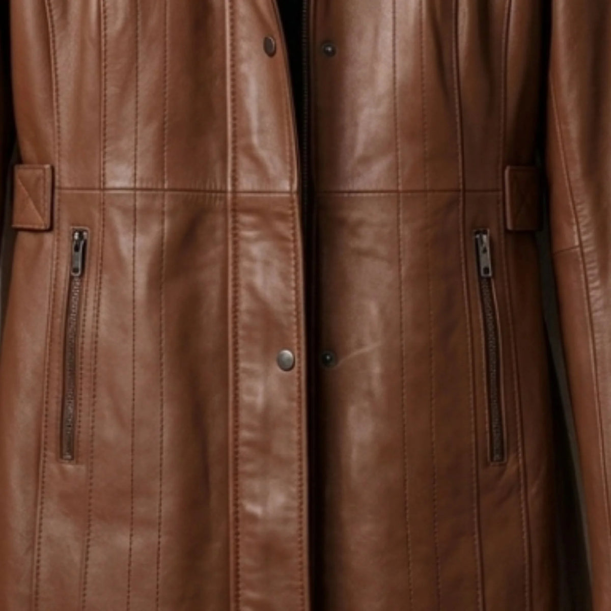 Zip pockets and front closure detail on women’s long brown leather coat
