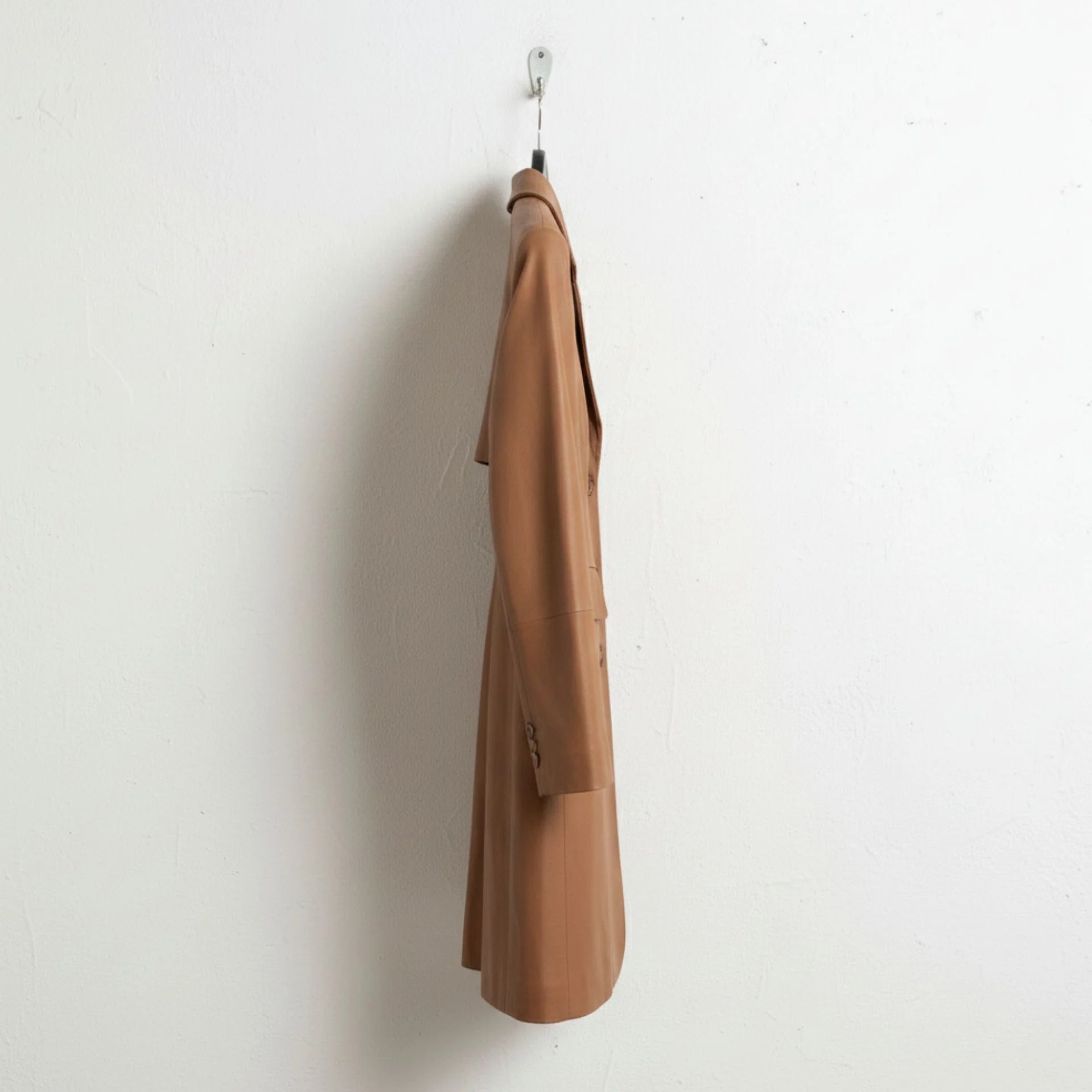 Side profile of tailored women’s brown leather coat mid‑thigh length