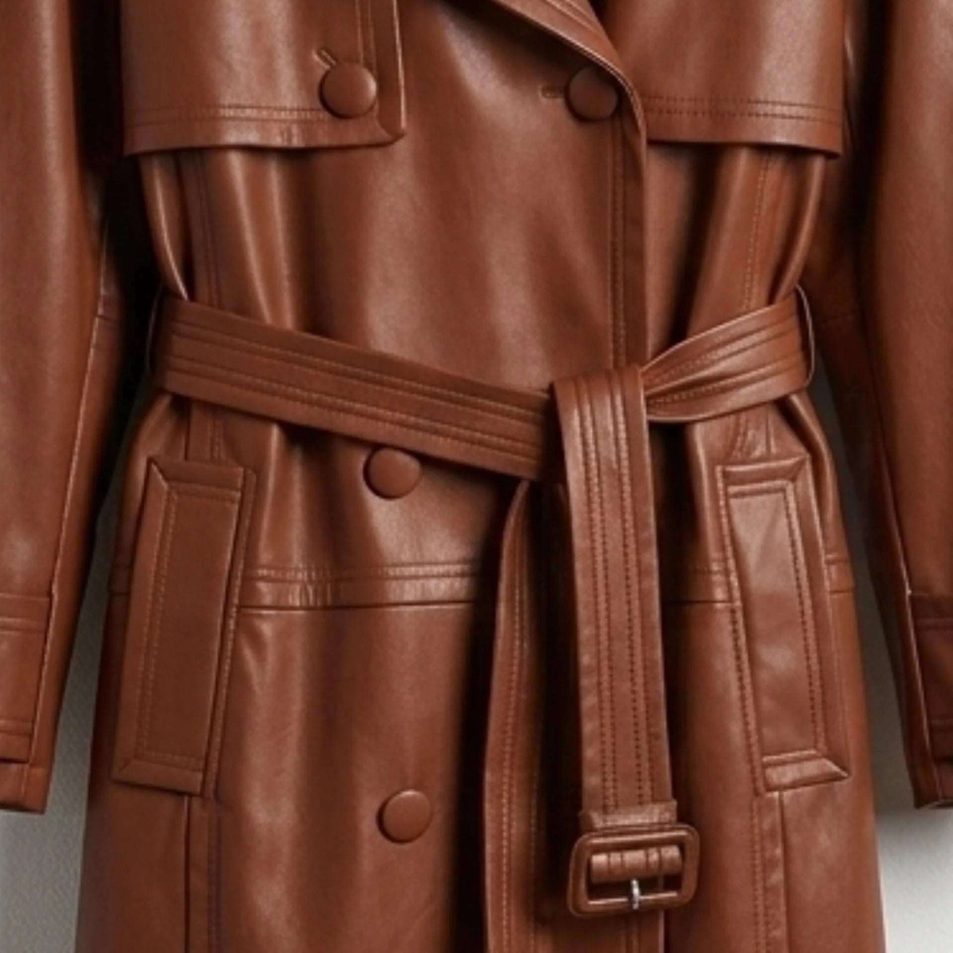 Belted waist, pockets and covered buttons on long brown leather coat
