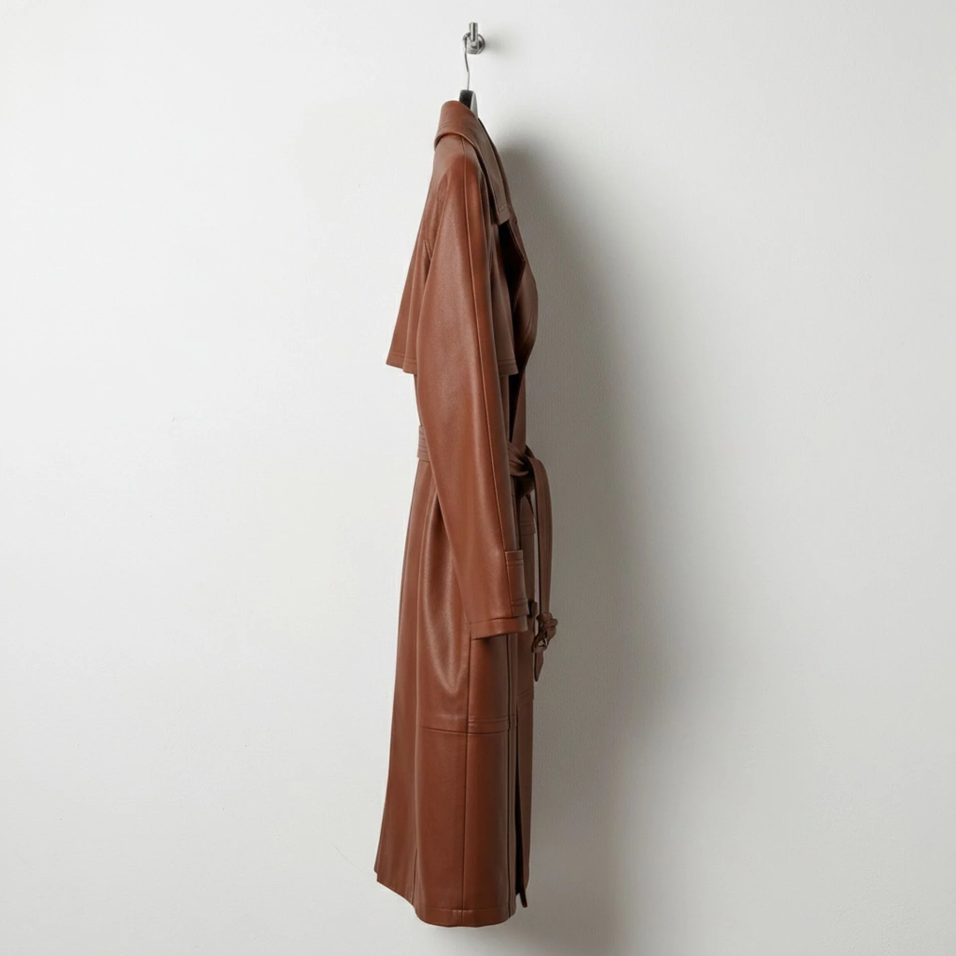 Side profile of women’s brown leather long trench coat with belt