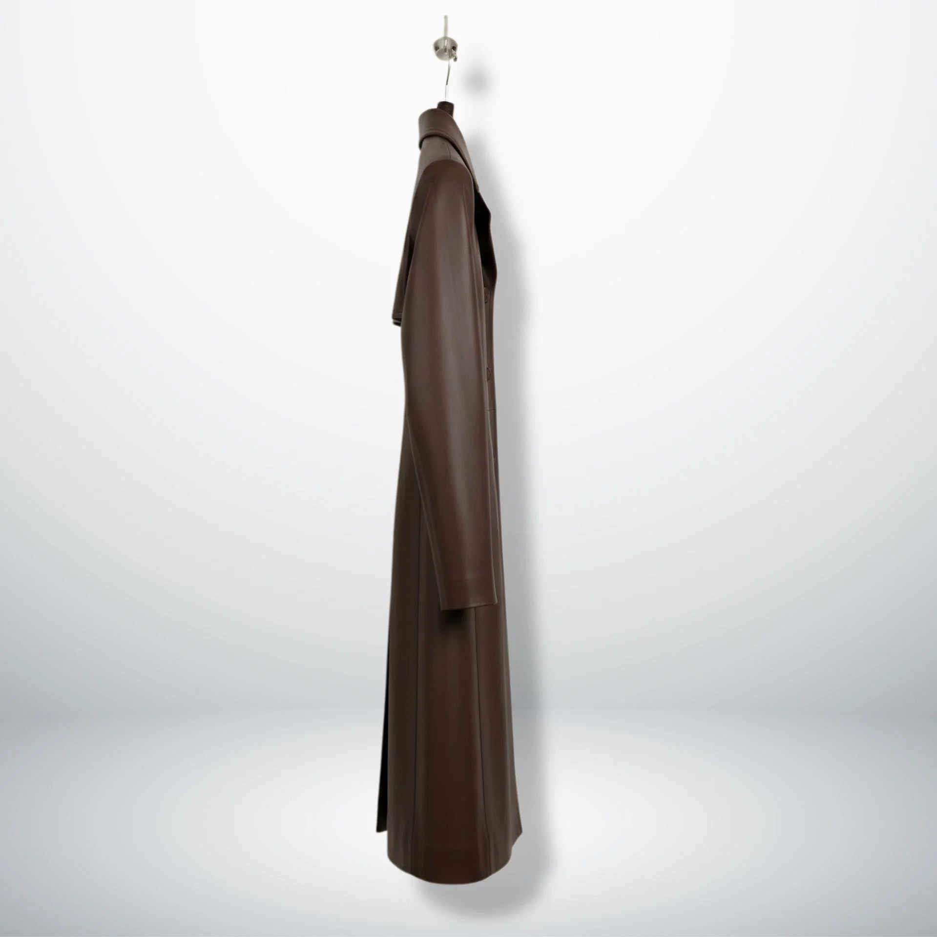 Side profile of women’s long brown leather overcoat showing straight fit