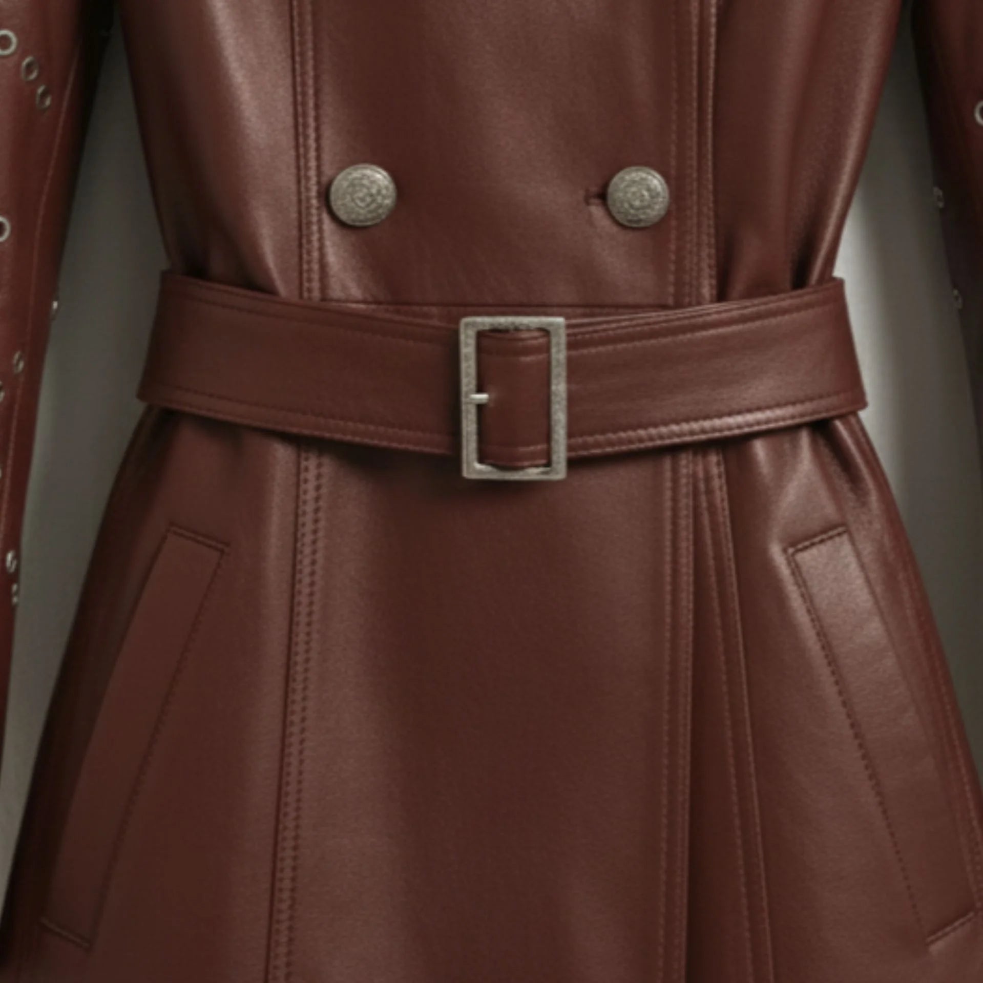 Belt and double breasted button detail on women’s maroon belted leather coat