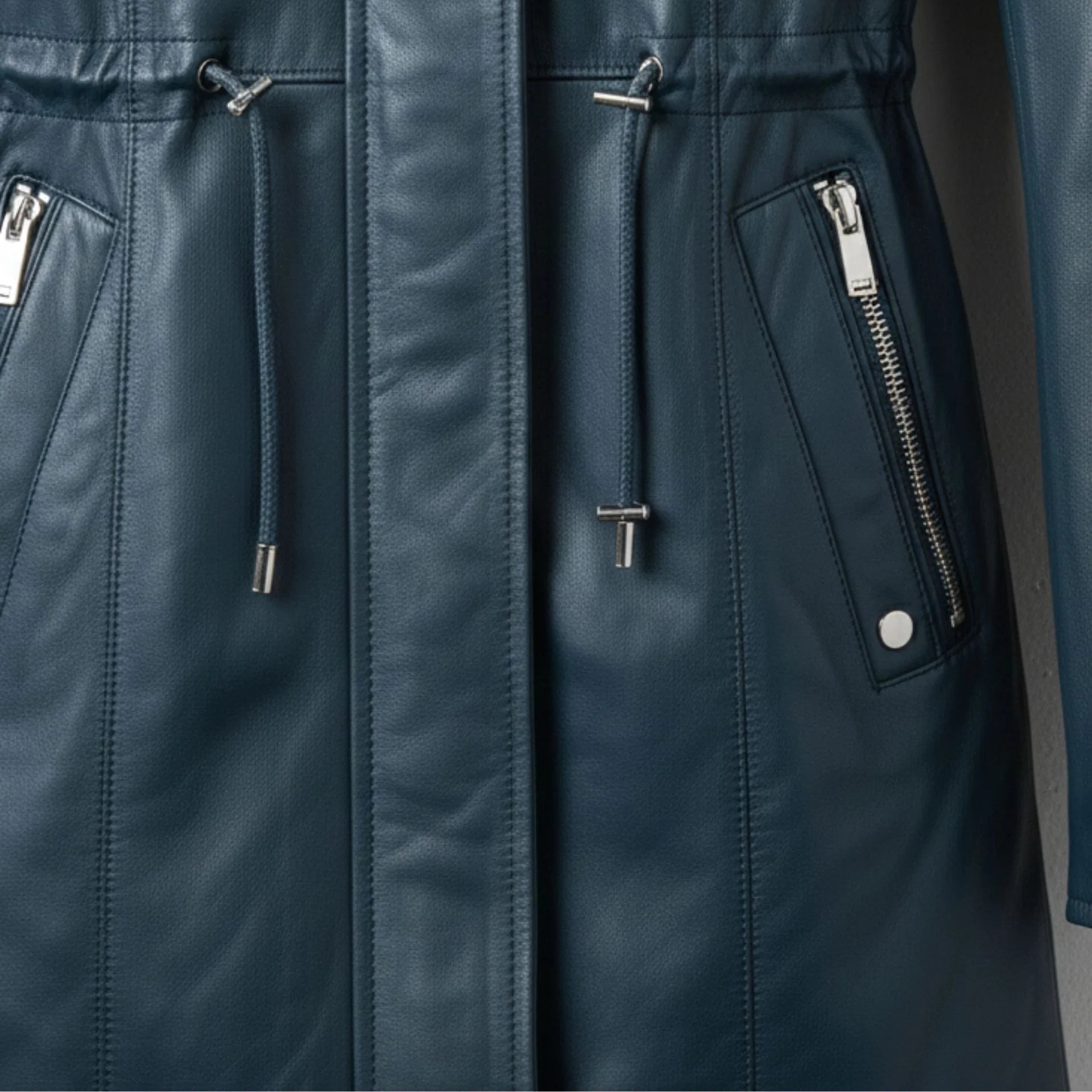 Drawstring waist and zip pocket detail on women’s navy hooded leather coat