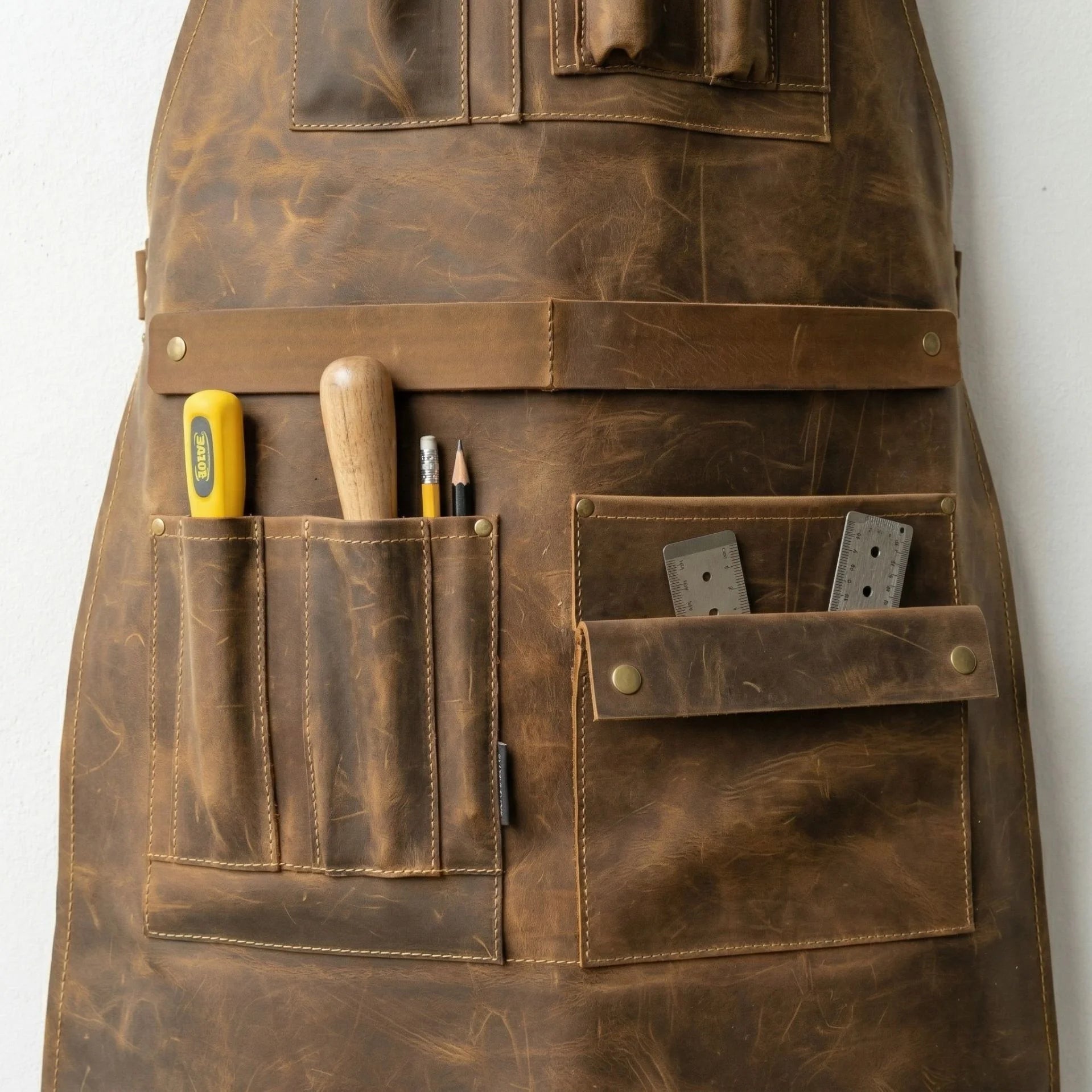 Close up of lower tool pockets on brown leather woodworking apron