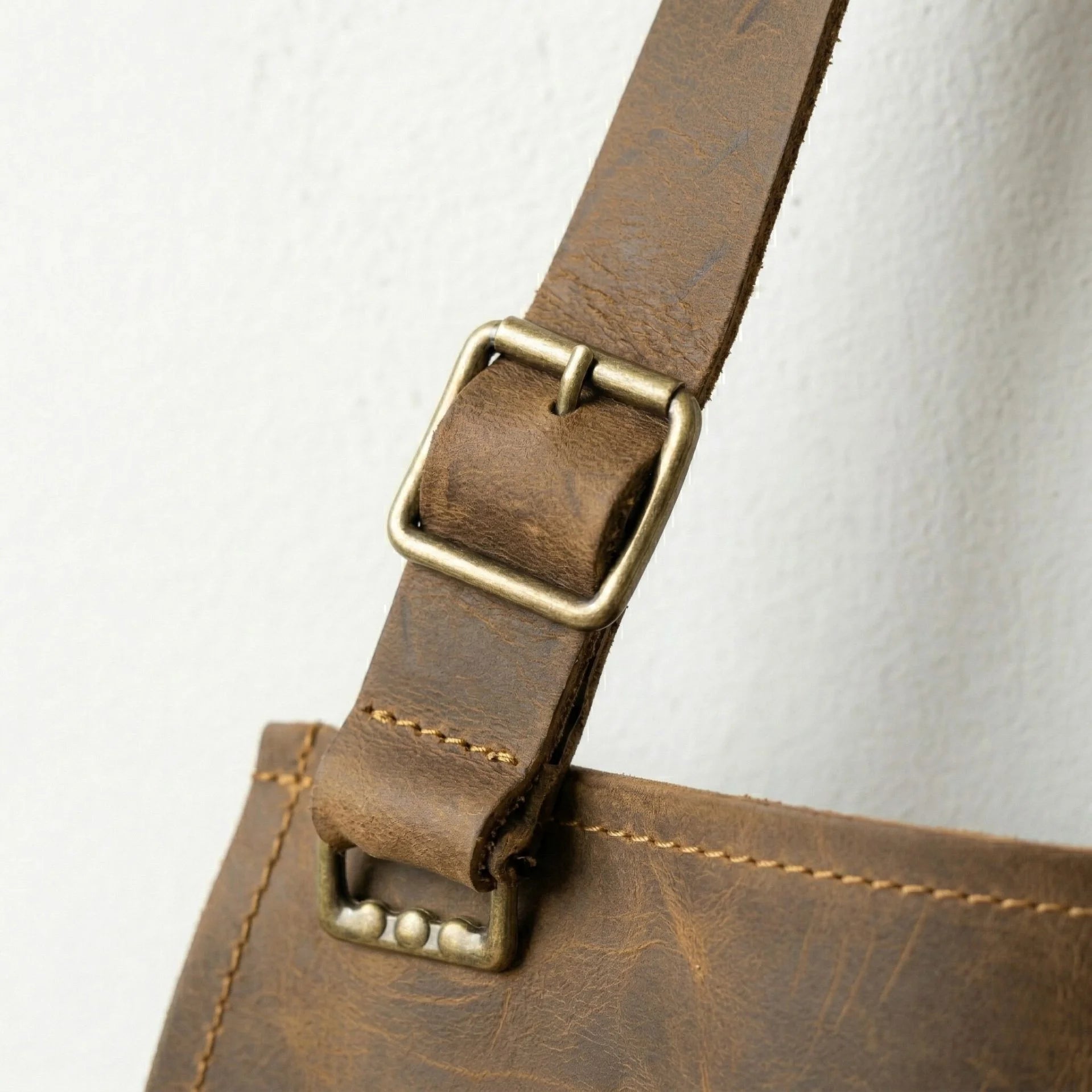 Close up of brass buckle on adjustable leather apron strap