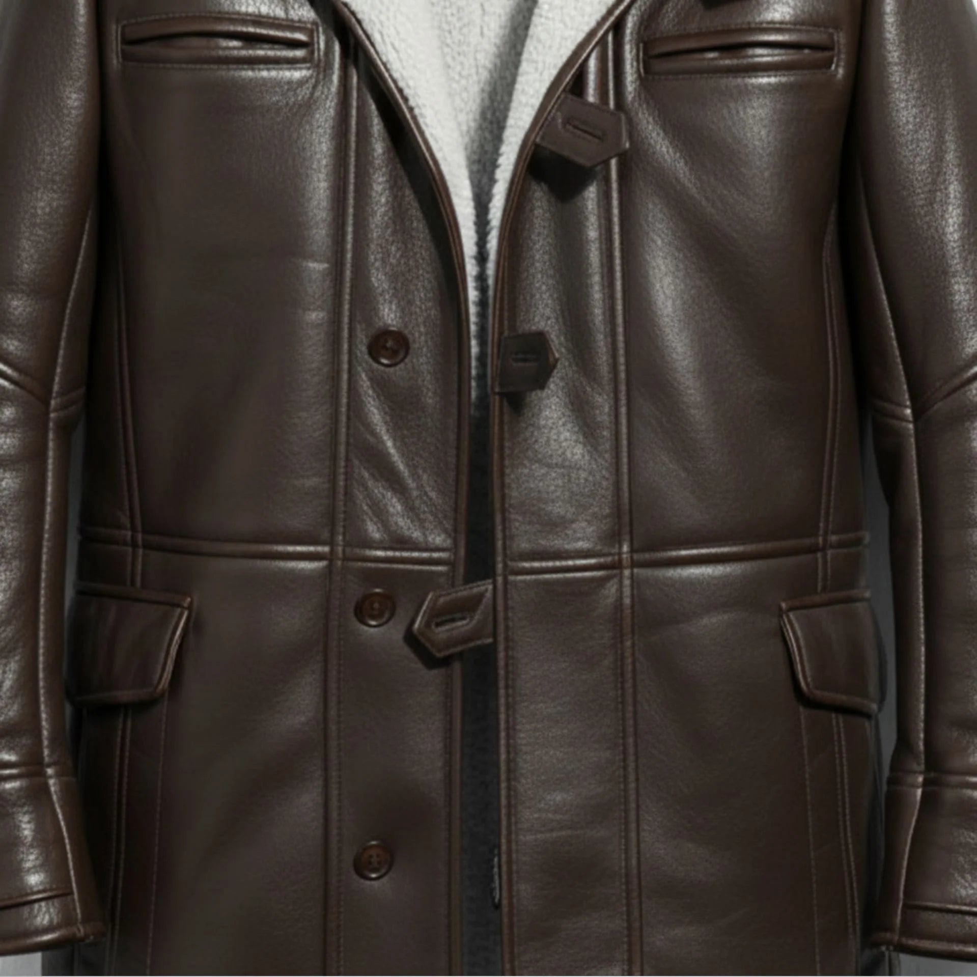 Close up of buttons, toggles and pockets on men's dark brown Bane leather coat.