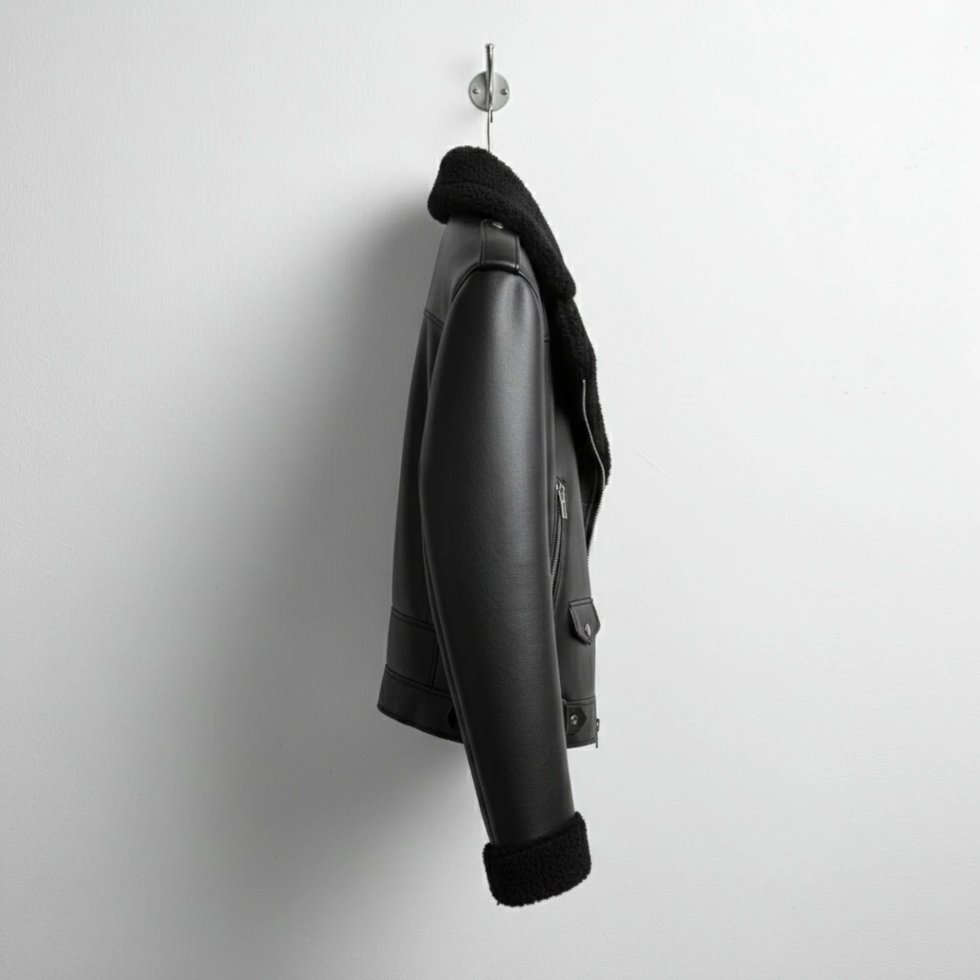 side profile mens black shearling aviator jacket hanging on wall.