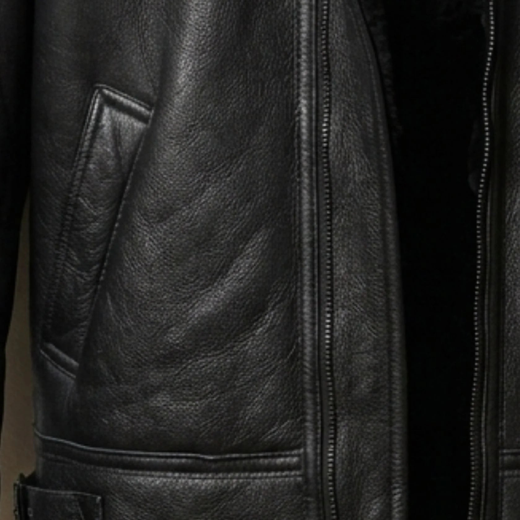 close up welt hand pocket and grain on mens black leather bomber jacket.