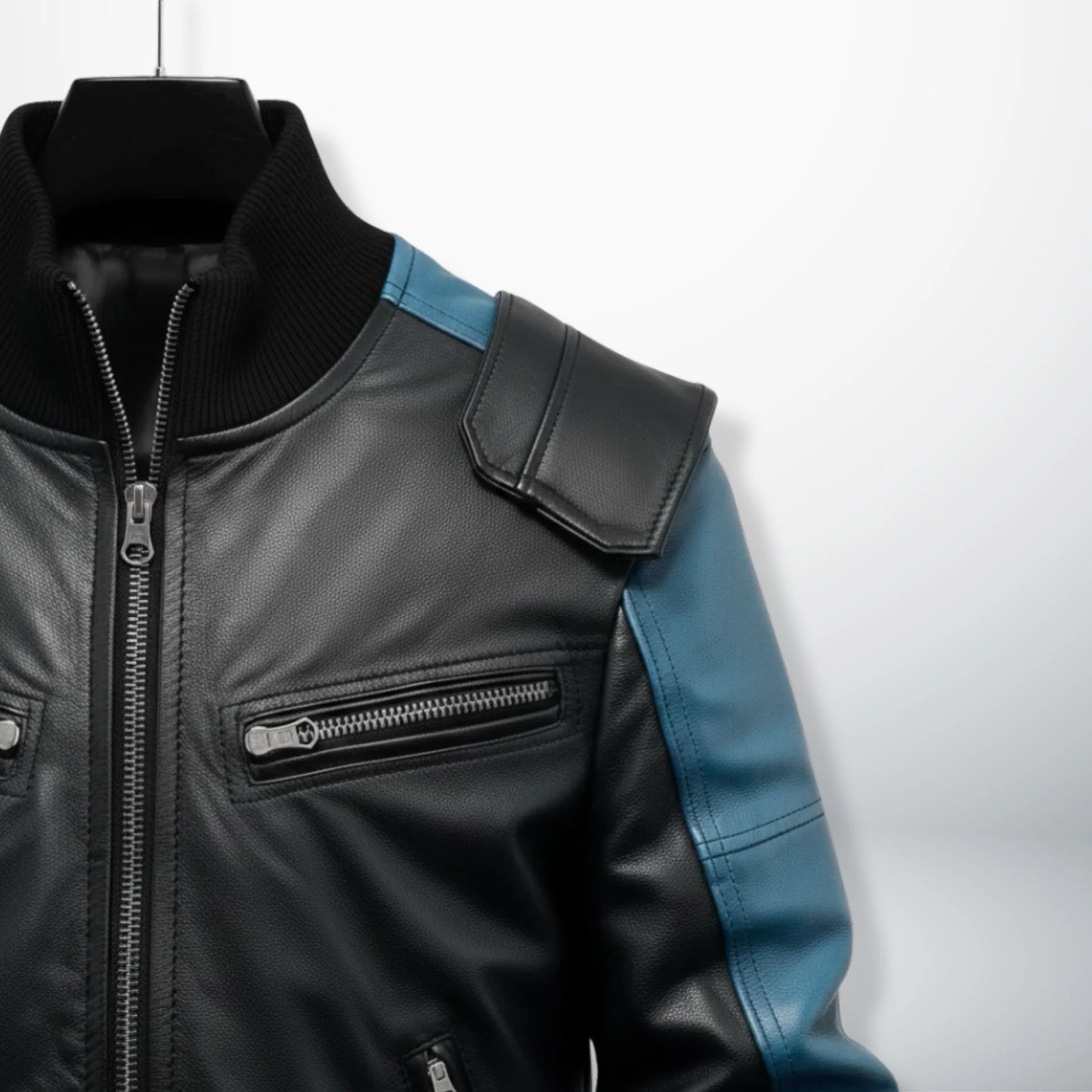 close up chest zipper pocket and shoulder panel on black and blue bomber jacket.