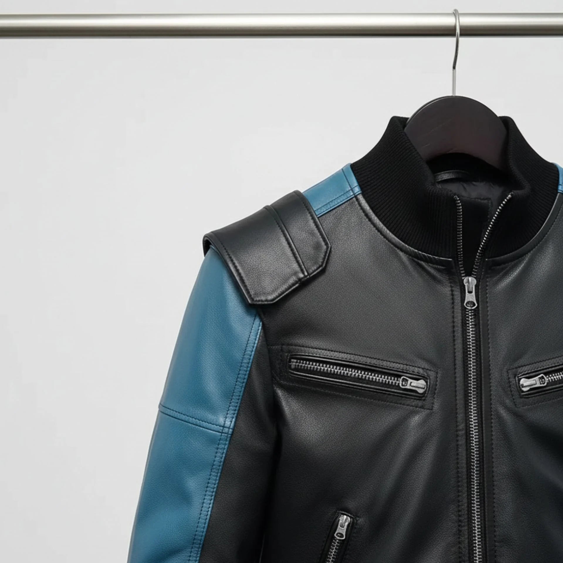 angled view mens black and blue bomber leather jacket hanging on rail.
